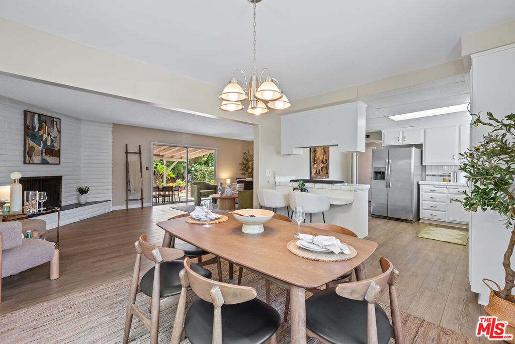 Nestled on an oversized corner lot in a peaceful Northridge neighborhood, this delightful residence offers an exceptional blend of comfort, style, and outdoor living. Privacy is paramount, thanks to the unique rounded corner position of the property, creating a serene and secluded atmosphere. A welcoming foyer sets the tone for the rest of the home. The thoughtfully laid-out floor plan separates the main living areas from the private bedroom quarters, ensuring a sense of peace and tranquility. The heart of the home is the oversized living room where a charming fireplace creates a focal point. The open floor plan connects the dining area and the kitchen which is equipped with stainless steel appliances, ample cabinet space, and a breakfast bar. The main bedroom serves as a private retreat, complete with an en-suite full bathroom and a relaxing bathtub. The guest bedroom is flooded with natural light and provides direct access to the backyard, along with a large walk-in closet. An additional guest bedroom could be a perfect home office. The spacious shared bathroom has been updated with elegant tiles and a glass shower. Sliding doors from the living area extend the living space to the outdoor patio, making it ideal for seamless indoor-outdoor entertaining. The expansive backyard is a true haven with a diverse array of mature trees, including delicious orange, lemon, guava, and Asian apple varieties. A shaded patio cover provides the perfect setting for al fresco dining. Multiple sitting areas throughout the yard encourage creative use of the large outdoor space. A two-car garage with a wide driveway offers ample parking and storage. Enjoy easy access to a variety of shops and restaurants including Porto's Bakery, all just moments away.