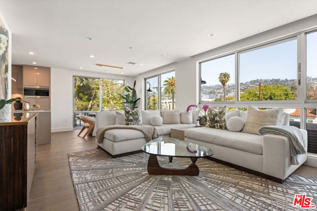 Experience elevated living with this rare penthouse unit just steps from the iconic Melrose Place and its star-studded farmers market. Located in the boutique Ainsley community, this residence offers sweeping city and Hollywood Hills views from every room and over 1,000 sq. ft. of wraparound terrace space perfect for morning coffee, sunlit workdays, and glamorous evenings under the stars. Inside, the open-concept design blends warm wood accents, natural stone, and a soft neutral palette to create a sophisticated, inviting atmosphere. The chef's kitchen features Sub-Zero and Wolf appliances, Caesarstone counters, and custom Italian cabinetry with a large center island ideal for entertaining. The primary suite offers terrace access, a walk-in closet, and a spa-inspired bath with soaking tub and oversized rainfall shower. The secondary bedroom doubles as a guest suite or home office with its own full bath and terrace access. Residents enjoy resort-style amenities including a state-of-the-art fitness center with Peloton bikes, yoga and Pilates studios, a stylish lounge, and a Zen courtyard with BBQs and communal dining. This penthouse also includes two rare side-by-side reserved parking spaces in the gated garage, a dedicated fast-charging outlet for electric vehicles, and a private storage room a truly exceptional convenience in West Hollywood.With world-class shopping, dining, and the celebrity-loved Melrose Place Farmers Market just outside your door, this home offers an unmatched lifestyle opportunity in one of L.A.'s most coveted neighborhoods.