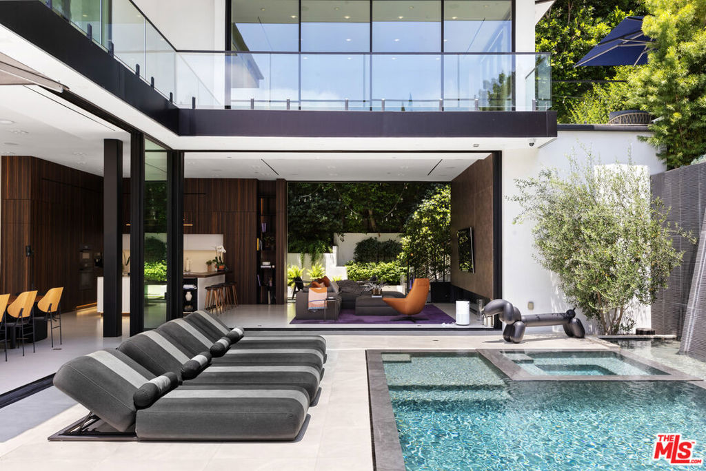 This ultra-private Organic Contemporary estate has been meticulously crafted to meet the highest standards of luxury. Encompassing approximately 7,000 square feet of voluminous living space, the home blends modern design with natural elements, offering exceptional scale and an abundance of natural light throughout. A dramatic entry begins at a custom double-height Brazilian Monkeywood pivot door, leading into a grand, light-filled foyer. Seamless indoor-outdoor living is achieved with disappearing walls of glass that open to an expansive pool area complete with an outdoor kitchen, BBQ, firepit and integrated smart home features throughout the property. Designed for both grand entertaining and intimate living, the residence includes four luxurious bedrooms all with en-suite bathrooms, a state-of-the-art home theater, a wine-tasting and billiards lounge, and a fully outfitted basement bar. The opulent primary suite offers a sanctuary of style and comfort. The one-of-a-kind rooftop deck, showcases panoramic views of the skyline - a perfect backdrop for sunset entertaining or quiet evenings under the stars. This is the perfect Hollywood Hills retreat. A true collector's home for the most discerning Buyer.
