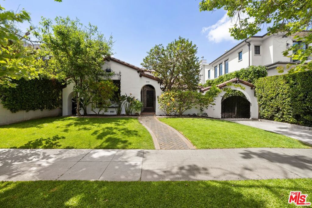 Lovely private Spanish oasis in the heart of Beverly Grove, just blocks from the Grove, fine dining, LACMA and the Beverly Center. Nestled in a quiet residential pocket, this 1930's romantic Spanish offers original details with modern amenities. Enter your new home through a gated courtyard into the entry with high circular turret and soak in the sunken living room that features soaring ceilings with exposed beams, a huge picture window and a magnificent fireplace. Separate dining room with original coved ceilings, bar counter/pass through to the kitchen and magnificent arched wood and glass doors that lead to the kitchen. The remodeled kitchen offers quartz counters, custom white cabinets and lovely eat-in area with built-in bench seating. The primary bedroom features new French doors that lead to a newly built deck that overlooks the grassy back yard and rear patio with pergola, perfect for entertaining and el-fresco dining. This residence includes 2 Additional oversized bedrooms, charming writing area, mostly brand-new windows and doors, 1 year old HVAC and wood flooring. The Tranquil backyard includes fruit trees, lush landscaping, a generous patio and a newly remodeled converted garage with bathroom, perfect for a studio, home office or guest suite.. With great charm and privacy, this is a home that rarely comes on the market and should not be missed.