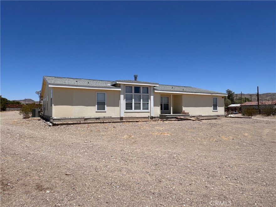This expansive 5-acre property on the North side of Barstow, located on Old Highway 58, offers a unique opportunity with two mobile homes. The front home, built in 2007 and is on permanent foundation, it features 4 bedrooms and 2.5 baths across 2,568 sqft. Inside, you’ll find a spacious living room with a two-way fireplace, a family room, and a large kitchen with an island and ample cabinetry. The primary suite includes an office space, walk-in closet, and a bathroom with a soaking tub and separate shower. There’s also indoor laundry with a utility sink and a covered back patio. Just behind the main home sits a smaller single-wide mobile home with 2 bedrooms and 2 bathrooms in 720 sqft. Due to the condition, this property will not qualify for traditional financing. Bring your imagination—with some updates and repairs, this property has the potential to truly shine.