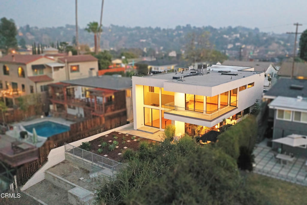 Discover this stunning modern duplex in the heart of Eagle Rock, designed by award-winning AIA architect Martin Fenlon. This architectural gem offers a perfect blend of contemporary design, functionality, and breathtaking 180-degree views of the city and hillsides. The main unit spans two levels, featuring three spacious bedrooms and two luxurious bathrooms. The open-concept living, kitchen, and dining areas create the ultimate entertainer's paradise, highlighted by floor-to-ceiling glass that frames spectacular views. A wrap-around balcony with sleek glass panels extends off the living room, offering a serene space for outdoor relaxation or entertaining. At the heart of the main level, the kitchen boasts exquisite granite countertops, high-end stainless steel appliances, and elegant modern cabinetry. The primary bedroom offers a walk-in closet and a spa-like ensuite bathroom with a jetted soaking tub and enclosed glass shower. Downstairs, a beautifully designed staircase leads to a large family room with two-story walls of glass that fill the space with natural light. Step outside to a landscaped backyard, which features a terraced lower level ready to be customized to suit your lifestyle. The second unit mirrors the same architectural finesse, featuring two comfortable bedrooms and two bathrooms. The cozy living and dining areas offer picturesque views, while the adjacent kitchen is both functional and tastefully designed. The primary bedroom includes its own private ensuite bathroom, and the second bedroom has convenient access to a full hallway bathroom. Additional highlights include hardwood floors, fireplace in each unit, recessed lighting, low-water landscaping, laundry facilities in each unit, central air and heat, a two-car garage, and driveway parking for two more vehicles. Ideally located, this property is just minutes from Eagle Rock's vibrant shops, restaurants, and entertainment options, including Trader Joe's, Casa Bianca, Cindy's, Little Beast, Vidiots, Sprouts, Senor Fish, Max City Barbeque, Four Cafe, Target, and more. The main unit is vacant and move-in ready, while the second unit is currently on a month-to-month lease, offering excellent income potential or flexibility for multi-generational living. Don't miss the opportunity to own this architectural masterpiece in one of Eagle Rock's most desirable neighborhoods.