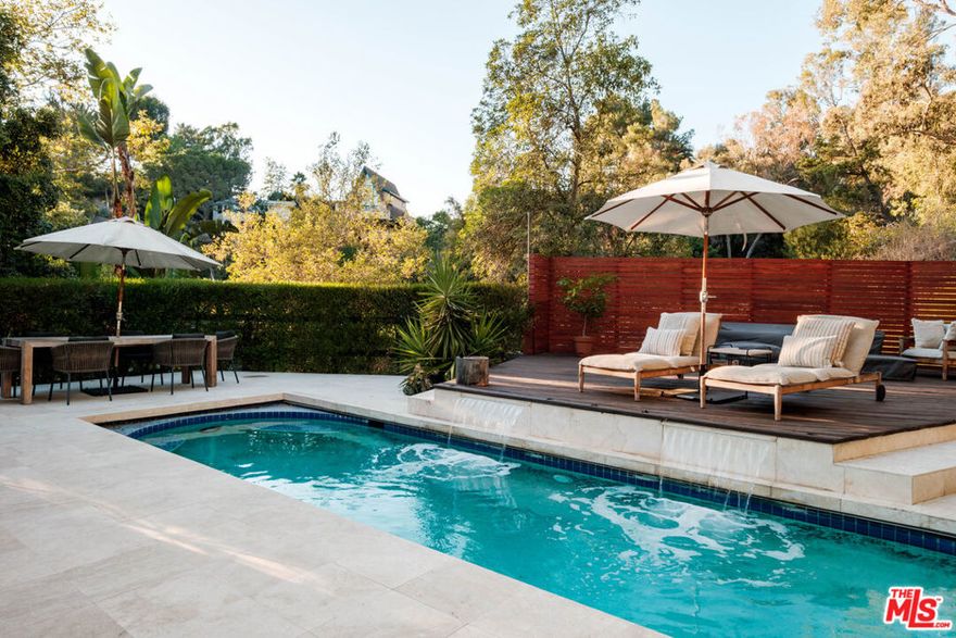 Perched above iconic Laurel Canyon and just moments from the Sunset Strip, this luminous mid-century modern flows effortlessly indoors and out for ultimate Hollywood Hills living. A chef's Viking kitchen with custom cabinetry and a bold island opens to a glass-walled living room crowned by nine skylights and a dramatic fireplace. Natural stone and wood floors lead to three bedrooms and two luxe baths, including a sun drenched primary suite that boasts a walk-in closet, spa bath, fireplace, and French doors opening to the resort-style outdoor living space. Saltwater pool, fountains, fire-pit, bar, outdoor shower, and multiple lounge/dining areas set the scene. The garage has been transformed into a sleek 300 SF art studio. The driveway and a private street space offer parking for 5 cars. Perfectly blending privacy and proximity, this elevated retreat offers an ideal balance of tranquility and city convenience. Whether entertaining beneath the stars or enjoying quiet mornings with canyon views, every moment here feels distinctly cinematic. Thoughtfully updated, yet true to its mid-century roots, this home captures the essence of Southern California living -- bright, open, and effortlessly sophisticated.