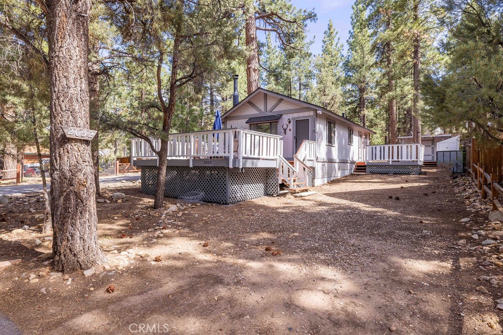 Set on a quiet corner lot surrounded by tall pines, this charming Erwin Lake cabin offers the perfect blend of comfort, character, and convenience. Whether you're seeking a peaceful full-time residence, a weekend escape, or a turn-key rental, this 2-bedroom, 1-bath getaway checks all the boxes. Inside, you'll find a warm, wood-accented living room with vaulted T&G ceilings, a classic stone fireplace with insert, and large windows that bring in natural light and tree views. The open layout flows into a dedicated dining space and a functional kitchen with a breakfast bar, wood cabinetry, and included appliances. Two cozy bedrooms feature mirrored wardrobes, and ceiling fans. Step outside to enjoy the fresh mountain air on not one, but two spacious decks—ideal for sipping morning coffee, grilling with friends, or simply taking in the stillness of the trees. Two gravel driveways provide plenty of parking for guests, and the two large storage sheds offer great space for tools, toys, or outdoor gear. Located on the desirable Mitchell side of Erwin Lake, you’ll enjoy a quieter side of Big Bear while still being just minutes from the lake, hiking trails, slopes, and local favorites. Sold fully furnished and ready to enjoy—this is easy mountain living at its best.