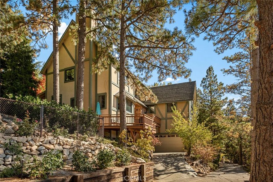 Remodeled Lake Arrowhead home with lake rights and a two-car garage. Lake and mountain views appear from multiple rooms, and the usable backyard extends the living space outdoors. Inside, the main level brings everyone together: an updated, open kitchen with solid-surface counters, refreshed lighting, and generous cabinetry flows to the dining area, where sliders open to a covered patio for year-round use. The living room centers on a classic brick fireplace, complemented by a bay-window bench that frames the view. The versatile layout offers four bedrooms plus a loft and an adjoining bonus room currently used as a fifth bedroom. The primary suite stands out with vaulted ceilings, a floor-to-ceiling stone fireplace, a spacious walk-in closet, and lake views. On the lower level, a large recreation room features wood-beamed ceilings, space for a pool table, a wet bar, and another fireplace—well-suited for gatherings or game nights. Outdoors, a terraced, low-maintenance yard pairs with a covered patio for easy indoor-outdoor flow. Located in Arrowhead Woods with lake rights, the property sits near trails, the Village, and marina amenities. Move-in ready and thoughtfully updated, it blends mountain character with modern conveniences.