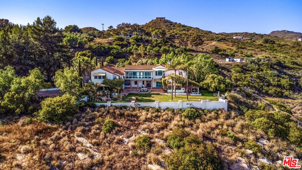 Charming Malibu Hills Tuscany Estate with Unparalleled 360 Views! Welcome to a truly enchanting sanctuary nestled in the heart of the Malibu Hills. An extraordinary Tuscany-inspired Villa set on approximately 12 acres of pristine, privately gated land. This one-of-a-kind property offers unobstructed 360-degree panoramic views of the Pacific Ocean and majestic surrounding mountains, creating a breathtaking backdrop from every angle. As you pass through the grand iron gates and wind down a tree-lined driveway, you are immediately transported into a world of serenity and luxury. The estate unfolds like a private resort, with multiple structures thoughtfully placed across the expansive grounds to maximize privacy, comfort, and the natural beauty of the landscape. The main residence, a stately two-story home, exudes timeless elegance with its classic Mediterranean architecture, warm stucco walls, and red-tiled roof. You'll be surprised to see the sprawling spaces inside. Just few steps away, a detached two-story guest house offers three spacious bedrooms and three full bathrooms perfect for hosting guests or extended family in complete comfort and style. At the heart of the estate lies a massive sparkling pool and spa, surrounded by vast sun-drenched decks and lush landscaping. The pool cabana is a showstopper in itself, featuring soaring ceilings, a cozy fireplace, a full bath, and a tranquil massage room, ideal for relaxing after a swim or entertaining under the stars. Equestrian enthusiasts will be delighted by the giant, all-flat, fenced horse arena, which can also be repurposed for events, sports, or creative outdoor uses. The property also includes horse stables, a chicken coop, and a large storage building, offering both functionality and charm. The grounds are a masterpiece of thoughtful design and natural beauty. Manicured grassy lawns roll gently across the property, dotted with fruit trees, soothing fountains, and a koi pond complete with a picturesque round wooden bridge. A romantic gazebo invites quiet moments of reflection, while massive solar panels and a private well ensure sustainable, off-grid living. Additional features include a three-car garage, caretaker's quarters, and multiple outdoor lounging and dining areas that take full advantage of the estate's awe-inspiring views. Whether you're watching the sun rise over the mountains or set into the ocean, every moment here feels magical. This Malibu Hills estate is more than just a home, it's a lifestyle. A rare blend of luxury, privacy, and natural splendor, it offers a once-in-a-lifetime opportunity to own a piece of paradise. Whether you're seeking a peaceful retreat, a family compound, or a venue for unforgettable gatherings, this property delivers it all with grace and grandeur.