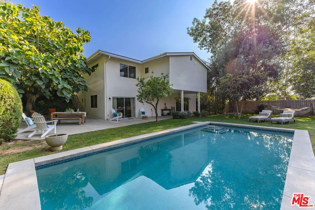 Tucked high at the end of a quiet cul-de-sac, this Mid-Century Modern retreat offers the perfect balance of privacy, design, and convenience. Nestled between the relaxed energy of Eagle Rock and the natural beauty of the Pasadena Arroyo, you're just minutes from Eagle Rock's eclectic dining and shopping, the Rose Bowl, and Old Town Pasadena. From a casual dinner at Little Beast to a pick me up at Little Flower or just a stroll around the Rose Bowel's track, everything is close by. Set on a rare 15,000+ sq ft lot, the home features four bedrooms and four-and-a-half baths, with every bedroom enjoying its own en suite, an elevated suite-style layout that ensures comfort and privacy for all. The main level unfolds in a sunlit open floor plan anchored by a chef's kitchen with a striking limestone island. A vintage white Malm fireplace centers the living room, where architectural windows frame sheltering fig trees. The dining area glows beneath an amber globe chandelier, capturing golden mountain views, while a stylish powder room sits conveniently nearby. Upstairs, three spacious bedrooms offer picture-perfect views of the pool and greenery. Each bath is finished with hand-carved marble vanities, custom tilework, rainfall showers, and deep soaking tubs. The lower level adds a second expansive living space, ideal for entertaining, holiday gatherings, or movie nights with its drop-down silver screen. The opposite wing houses the dramatic primary suite, designed with soaring ceilings, a generous walk-in closet, and a bespoke bath with double vanity. Outdoors, the property transforms into a private resort. A sparkling pool is framed by lush lawn, mature landscaping, and a stately fig tree that creates a natural canopy. The grounds invite al fresco dining, hammock lounging, starlit gatherings, twilight swims, or even projecting films against the house. Private yet connected, tranquil yet vibrant, this one-of-a-kind retreat embodies the essence of California living at the crossroads of Eagle Rock and Pasadena.