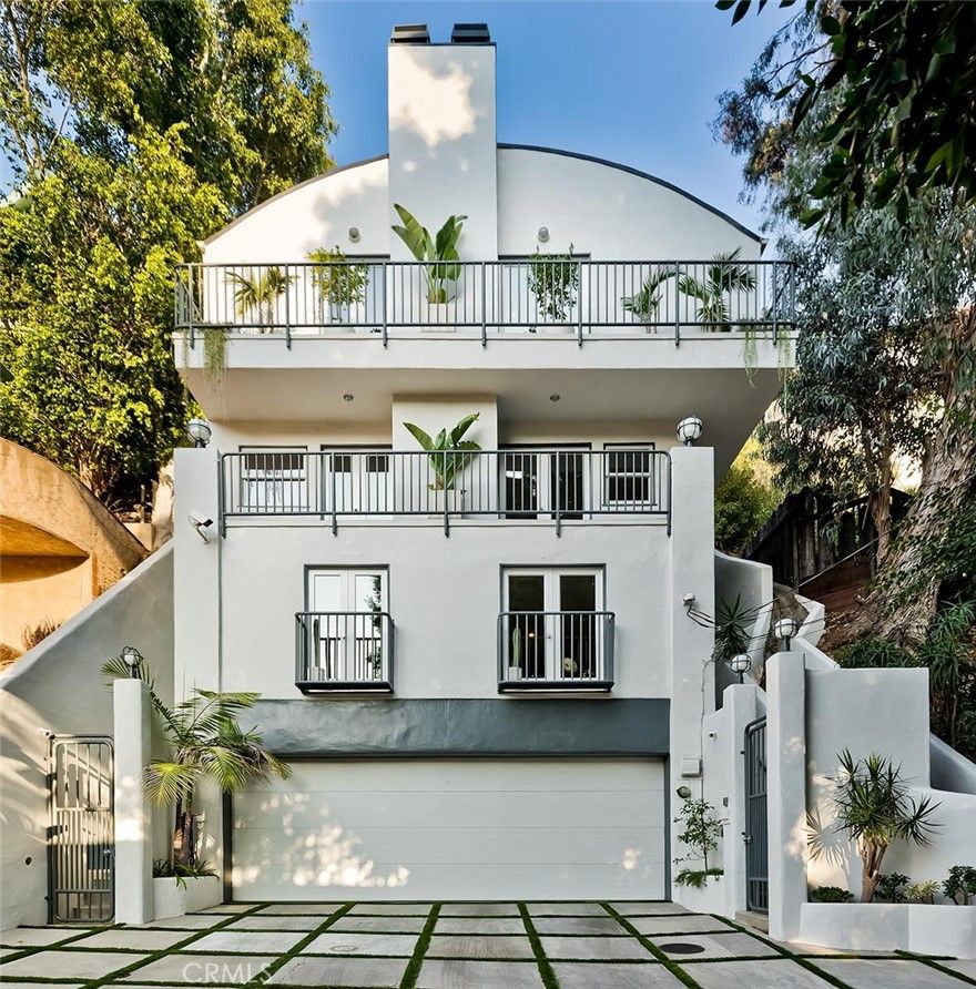 Perched in the coveted hills of Laurel Canyon, this striking residence offers a rare blend of mid-century character and modern luxury, framed by sweeping Hollywood Hills views and lush natural surroundings. Designed for seamless indoor-outdoor living, the home delivers privacy, style, and an unmistakable sense of California sophistication—just minutes from West Hollywood and Beverly Hills. The main residence features three well-appointed bedrooms across multiple levels, filled with natural light from expansive windows and glass doors. Open-concept living and dining areas showcase refined finishes, curated design details, and effortless flow to outdoor entertaining spaces. The primary suite serves as a private retreat with a spa-inspired ensuite bath and direct access to an outdoor deck. Outdoor living is a standout feature, highlighted by a private swimming pool and spa with breathtaking canyon and hillside views. Surrounded by mature landscaping and multiple lounging areas, the outdoor spaces offer an ideal setting for relaxation, entertaining, and enjoying spectacular sunsets. A separate, private-entry studio with an ensuite bathroom provides exceptional flexibility for guests, or a creative workspace. Thoughtfully designed with a seamlessly integrated Murphy bed, the space easily transitions between open living and comfortable sleeping quarters. The home is further enhanced by a chef’s kitchen with high-end Thermador appliances, central air conditioning, integrated sound system, EV charging, and exceptional parking capacity rarely found in the Hollywood Hills—including a three-car garage plus additional driveway parking. All indoor and outdoor furnishings are included, featuring designer-quality pieces that complement the home’s architecture and lifestyle. Recent upgrades include a torch-down roof, skylights, and plumbing improvements, offering added efficiency and peace of mind. Located on a quiet street, the property provides a serene setting while remaining close to premier dining, shopping, entertainment, and cultural landmarks throughout Los Angeles. Set in one of LA’s most storied neighborhoods, this Laurel Canyon residence presents a rare opportunity to own a distinctive hillside home with exceptional views and resort-style amenities.