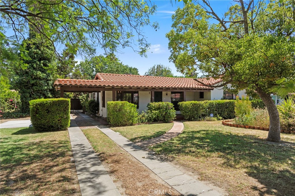 Welcome to this charming Spanish-style home full of character and potential, tucked away on a well-kept street in the heart of San Bernardino. As you pull up, you’ll notice the beautiful mature trees and a wide, green lawn that give this home great curb appeal. Step inside and you’re greeted by a spacious living room with high wood-beamed ceilings, original hardwood floors, a cozy fireplace, and vintage wall sconces that add tons of charm. To one side of the house, there’s a formal dining room perfect for hosting dinner with family and friends, a quaint kitchen with an adjacent breakfast nook featuring built-ins—great for your morning coffee—and a separate laundry room with plenty of storage. On the opposite side, you’ll find three generously sized bedrooms and two bathrooms, including one that’s been nicely updated with new vinyl flooring, a modern vanity, and a refreshed shower. At the heart of the home, overlooking the peaceful backyard, is a cozy family room with a wood-burning stove and Spanish tile flooring—such a warm and inviting space to relax. Natural light pours in through large windows throughout the home, and the private, shaded backyard is ideal for unwinding or entertaining guests. There’s also a detached 2-car garage that was previously used as a workshop, giving you extra space for hobbies, projects, or storage. The tile roof was replaced in 2016 and new HVAC units were installed in 2022! This home’s timeless design, spacious layout, and unique details make it a rare opportunity to bring your vision to life. Don’t miss it!