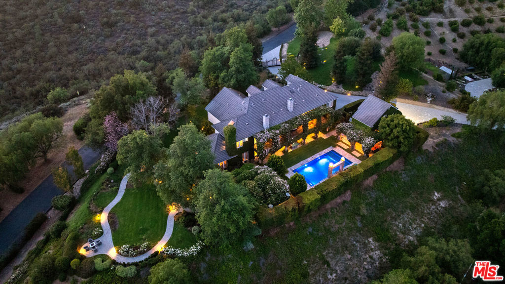 Set against the backdrop of breathtaking Santa Rosa Valley and mountain views, Rocking Horse Ranch is a 20.93-acre dream estate that strikes the perfect chord between rustic charm and luxury living. Tucked within a private, gated equestrian enclave where bridle paths weave through the community, this Country French-style retreat is more than just a home - it's a lifestyle. Step inside the 6,731-square-foot main house and find a harmony of style and space, boasting 7 bedrooms and 6 bathrooms. This estate knows how to entertain, with beautifully landscaped areas (designed by Wendy Harper of Gardens of the World) that provide the perfect setting for hosting everything from intimate get-togethers to crowd-pleasing outdoor events. A detached (approx) 1200 sf 2-level pool/guest house/recording studio with living space, bath area, kitchen and laundry area overlooks it all, is ready to inspire your next composition or host your favorite guests. For the horse enthusiast, the property features a 6-stall barn with turnouts, a mini kitchen, and a tack/sitting roomperfect for pre-ride chats or post-ride cool-downs. The star attraction is the regulation-sized riding arena with grandfathered lights and a viewing standa rarity in Santa Rosa Valley that's ready to host any equestrian performance. There's also a hot walker, washing station, and even a luxe chicken coop resort. But it's not all boots and saddles. This estate has plenty of space to kick back and enjoy the good life. Wander through the avocado grove, tend to the greenhouse and rose garden, or perfect your short game on the putting greenwhich doubles as an outdoor venue for movie nights under the stars. And don't miss the gentle fenced path to a lush, flat grass area, perfect for hosting everything from rustic weddings to soccer practice to memorable barbeques while taking in the Santa Rosa Valley views. The main residence presents high ceilings, custom library/office, a music room, and gathering area with fireplace and sun room that flows into the spectacular outdoor entertainment spaces. The kitchen is a chef's arena, showcasing Sub-Zero refrigerator and freezer, 2 Dacor ovens, a 48-inch Thermador stove top w/BBQ, 2 Miele dishwashers, and 2 islands big enough for your entire crew. Nearby, the formal dining room comes complete with a bar and service area, ideal for cocktails and conversation. On the first floor, a full-bedroom suite with a private entrance is perfect for guests or au pair. Upstairs, the primary suite is pure indulgence, with a cozy fireplace, French doors leading to a sprawling balcony, and a mini kitchen for morning coffee or late-night snacks. Five spacious additional bedroom suites complete this level. Four fireplaces and heated floors add to the home's warm appeal while integrated speakers, Creston automation and video security systems supply smart home features at your fingertips. There is an oversized 4-car garage and ample guest parking behind the entry gates. And when the lights go down? Head to the upper-level movie room with a bar, or step out to the exceptional pool and spa area, where a waterfall wall, fire features, and three covered gathering spaces set the stage for unforgettable evenings. The detached covered outdoor living room features a large fireplace, TV, outdoor kitchen and bar. Whether you're throwing unforgettable pool parties, riding the trails or simply soaking in the sunsets, this estate is where country dreams and artistic inspiration come together in perfect harmony.