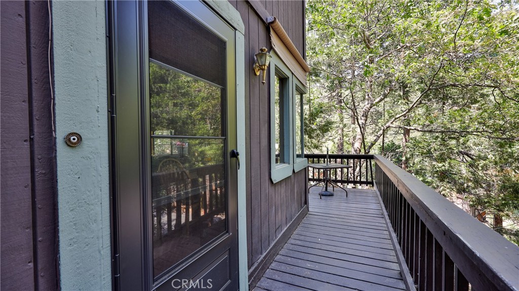 If you're seeking that perfect treehouse feel, this Cozy Cabin is an excellent match. Upon arrival, you'll drive up a gently sloped driveway that leads to a well-built set of cement stairs, offering easy access to this charming 3-bedroom, 1.5-bath property. The main level features a functional kitchen with ample cabinetry and plenty of prep space, making it a great fit for everyday cooking or weekend entertaining. Adjacent to the kitchen, the dining area includes a large set of windows that offer stunning views of the surrounding trees.
The living room boasts open-beamed wood ceilings and a cozy fireplace, perfect for enjoying those colder winter evenings. Also on this level is a small bedroom, providing added convenience and flexibility. Head upstairs via a wide, solid wood staircase to find two additional bedrooms and a full bathroom, with one of the bedrooms offering direct access to the bath.
Step out the back door to a spacious deck that overlooks a terraced yard. The outdoor area includes a horseshoe pit and a fenced section, perfect for pets.