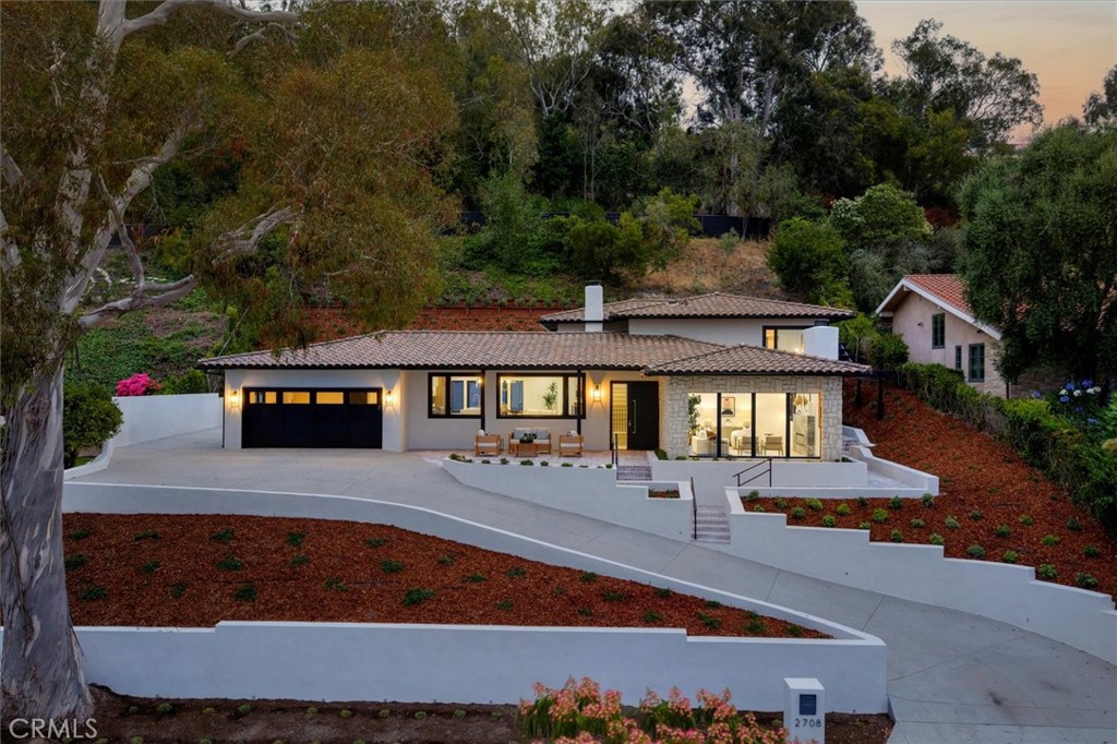 Welcome to this exquisitely remodeled residence nestled on one of Upper Malaga Cove’s most prestigious cul-de-sac streets, where refined design meets the quintessential Palos Verdes lifestyle. Perched gracefully above the road, the home is introduced by an expansive brick patio that showcases views of the coastline, city lights, and tranquil ocean horizons—a perfect vantage point for morning coffee or sunset gatherings. The exterior is graced with timeless PV stone details that blend beautifully with the surrounding architecture. Step inside to discover European oak floors flowing throughout the main living spaces, lending a warm yet modern ambiance. Vaulted ceilings in both the living room and kitchen enhance the sense of volume and light, creating an open, airy environment ideal for entertaining and everyday living. In the living room, a dramatic marble slab fireplace creates an elegant focal point, framed by thoughtfully curated lighting that elevates every corner. The kitchen is a showcase of custom craftsmanship, featuring white oak shaker cabinetry with glass-front doors illuminated by integrated LED lighting. A custom-designed curved-edge hood anchors the space above quartz slab waterfall edge countertops and backsplash, while the adjacent powder bath offers a statement floating marble vanity with an integrated marble sink—each detail meticulously envisioned and executed. Entertaining is effortless in the lower-level bar area, where white oak shaker cabinetry and floating shelves with under-shelf lighting create a welcoming environment for gatherings. Upstairs, the primary suite boasts beautiful coastline and city-light views that greet you each morning, a generous walk-in closet and a serene bathroom showcasing walls clad in large-format porcelain tiles, two sinks, a stand-alone soaking tub, and dramatic lighting—all contributing to the spa-like atmosphere. All bathrooms throughout the home are finished with decorator fixtures, and each tile selection was custom designed and curated to create a cohesive and sophisticated feel. On the lowest level is a thoughtfully designed guest suite with a private entrance and a spacious en-suite bathroom, perfect for visiting family or long-term guests. The upper backyard offers a peaceful grassy retreat with sweeping coastline, ocean, and city views, completing this exceptional offering. This is a rare opportunity to own a turn-key, design-forward property in one of Palos Verdes’ most coveted enclaves.