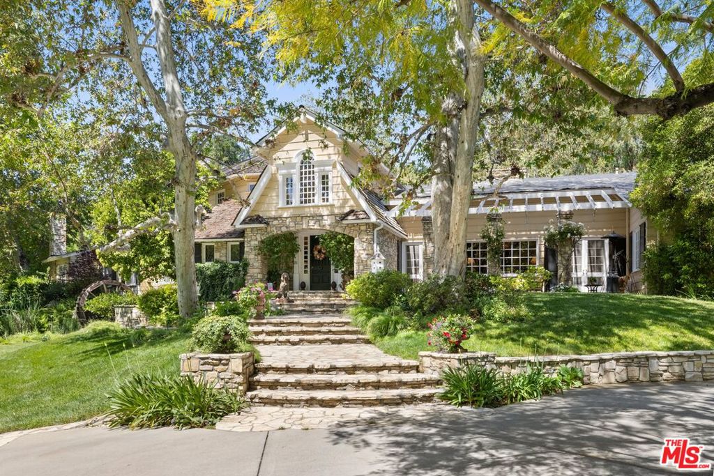 One of the most extraordinary compounds in all of Southern California, this legendary estate with ties to Walt Disney encompasses 4.44 sprawling acres and blends East Coast elegance with Old Hollywood grandeur in a extremely private setting that feels worlds away from city life. Originally custom-built for renowned Academy award winning director/actor John Huston, this traditional home was crafted with a magical, enduring level of craftsmanship that's increasingly rare in today's architecture. Walt Disney- an avid train enthusiast later brought his vision to the property, helping to design the now-iconic Tunnel, Cut & Trestle Railroad: a fully operational 7.5" gauge miniature train that winds through the estate, complete with a working depot, turntable, bridges, and a fascinating tunnel that is over 240 ft in length. The 17,181 sqft gated compound includes a 12,170 sqft main residence with 6 bedrooms, 10 bathrooms, 9 fireplaces, a grand primary suite, and a lower 1,222 sqft covered terrace. The design integrates nature at every turn windows frame verdant views, and a resort-style, stone-framed pool with a spa creates a striking focal point as it partially flows beneath the home. Extending beyond the residence, the grounds unfold like a vast scenic park with rolling lawns, koi ponds, winding stone paths, and enchanting vignettes with shaded seating areas that evoke a sense of tranquility and timeless charm. A full-size lighted tennis court and multiple outdoor fireplaces are seamlessly woven throughout, offering space for both large-scale entertaining and peaceful retreat. Whether hosting weddings, community train days, or quiet afternoons under the trees, the estate effortlessly balances fantasy and functionality.Anchoring the estate is a newly constructed 2,775 sqft red barn, reimagined as a dramatic entertaining lodge with a full kitchen, 1 bedroom, loft, bar, and 2 bathrooms. Original barnwood was repurposed beneath the bar to preserve its rustic soul. A guest cottage (807 sqft) and train station with additional storage (1,882 sqft combined) along with off-street parking for over 20 cars round out the architectural ensemble. A one-of-a-kind storybook retreat with Hollywood provenance and enchanting, expansive grounds this is a legacy estate, a playground for generations, and a place unlike any other.