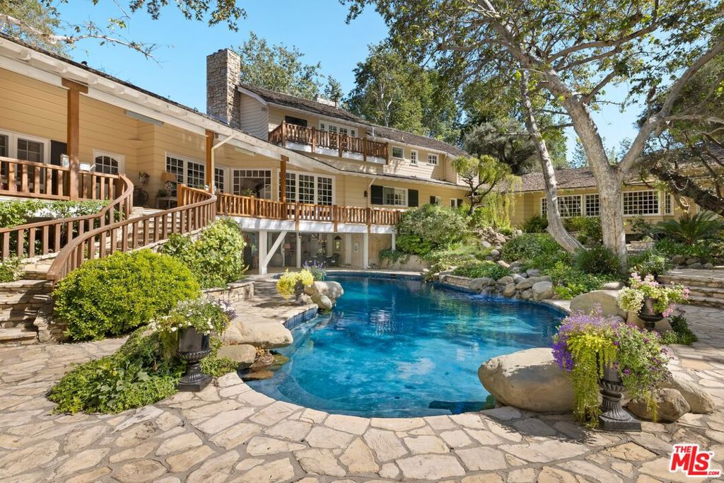 Must See to Believe!! One of the most extraordinary compounds in all of Southern California, this legendary estate with ties to Walt Disney encompasses 4.44 sprawling acres and blends East Coast elegance with Old Hollywood grandeur in a extremely private setting that feels worlds away from city life. Originally custom-built for renowned Academy award winning director/actor John Huston, this traditional home was crafted with a magical, enduring level of craftsmanship that's increasingly rare in today's architecture. Walt Disney- an avid train enthusiast later brought his vision to the property, helping to design the now-iconic Tunnel, Cut & Trestle Railroad: a fully operational 7.5" gauge miniature train that winds through the estate, complete with a working depot, turntable, bridges, and a fascinating tunnel that is over 240 ft in length. The 17,181 sqft gated compound includes a 12,170 sqft main residence with 6 bedrooms, 10 bathrooms, 9 fireplaces, a grand primary suite, and a lower 1,222 sqft covered terrace. The design integrates nature at every turn windows frame verdant views, and a resort-style, stone-framed pool with a spa creates a striking focal point as it partially flows beneath the home. Extending beyond the residence, the grounds unfold like a vast scenic park with rolling lawns, koi ponds, winding stone paths, and enchanting vignettes with shaded seating areas that evoke a sense of tranquility and timeless charm. A full-size lighted tennis court and multiple outdoor fireplaces are seamlessly woven throughout, offering space for both large-scale entertaining and peaceful retreat. Whether hosting weddings, community train days, or quiet afternoons under the trees, the estate effortlessly balances fantasy and functionality.Anchoring the estate is a newly constructed 2,775 sqft red barn, reimagined as a dramatic entertaining lodge with a full kitchen, 1 bedroom, loft, bar, and 2 bathrooms. Original barnwood was repurposed beneath the bar to preserve its rustic soul. A guest cottage (807 sqft) and train station with additional storage (1,882 sqft combined) along with off-street parking for over 20 cars round out the architectural ensemble. A one-of-a-kind storybook retreat with Hollywood provenance and enchanting, expansive grounds this is a legacy estate, a playground for generations, and a place unlike any other.