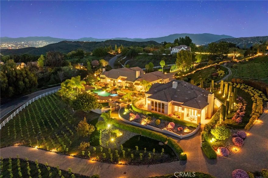 One-of-a-kind estate located just 5 minutes from the charm & culture of Old Town Temecula. Set behind 3 private gated entrances, this sprawling 4.19 acre compound features 3 separate single-story residences & an underground wine cellar all totaling approx. 6100 sq ft, masterfully positioned to capture breathtaking sunset views across rolling hills. The grounds truly set this estate apart; meticulously manicured landscapes framed by stately Italian cypress trees create an outdoor setting unlike any other. A dramatic stone stairway leads from the main home to the elevated studio residence. Entertain w/ ease and elegance w/resort style amenities; sparkling pool, two separate spas, water features, outdoor fireplaces, 2 putting greens, a sports court, & a post-tensioned tennis court w/ breathtaking views. Plus 2 built-in BBQ islands & pizza oven. Approx. 30,000 sq ft of stone pavers weave through the property. The main residence is approx. 3,275 sq ft w/ travertine flooring & architectural arches. It features 3 bedrooms, office, & 3.5 baths. The gourmet kitchen complete with granite countertops, 2 sinks, stainless steel appliances, built-in refrigerator, walk-in pantry, wine fridge, butler's pantry, & bar seating-all flowing seamlessly into the family room w/ views of the pool & gardens. The primary suite offers a private retreat w/ its own fireplace & French doors leading to the amazing pool & spa. The guest house offers approx. 1,600 sq ft of luxury living w/ 2 bdrms, 2 baths, a chef’s kitchen, & fully retractable glass doors opening to commanding views of the surrounding countryside. At the estate's highest point, the studio offers approx. 600 sq ft of open-concept living, complete with an elevated desk area, curved wine bar, a built-in spa, putting green, rooftop lounge, ATV-sized garage, & unmatched panoramic vistas. A 600 sq ft stand-alone reinforced concrete wine cellar is the perfect sanctuary for wine-making enthusiasts - complemented by approx. 1,000 wine grapevines and 21 table grapevines, as well as approx. 100 avocado trees, and various fruit trees. Additional features include upgraded mahogany garage doors, extensive landscape lighting, whole house & outdoor sound systems, multiple whole-house fans for year-round comfort, & a comprehensive security system. Perfect for a multigenerational compound, vineyard retreat, or entertainer's paradise, this Temecula estate redefines California luxury living with a setting that must be seen to be believed.