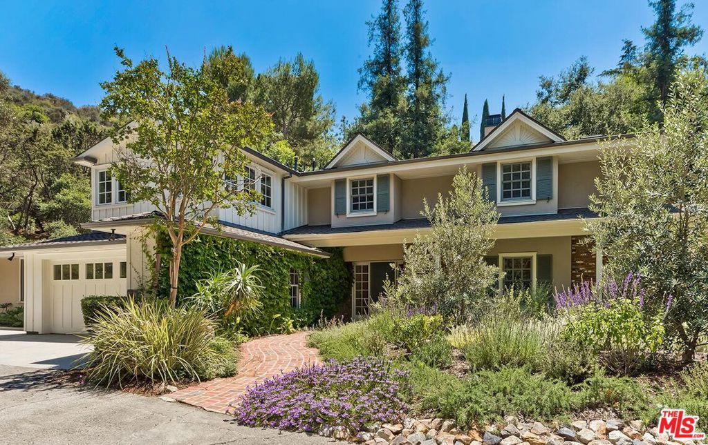 Sprawling traditional home offered for long-term lease in prime Hollywood Hills near Laurel Canyon Boulevard. This gated estate offers privacy, comfort, and a convenient central location. Set on nearly an acre of natural beauty, the 6,200-square-foot residence is nestled on a beautifully landscaped lot, perfect for enjoying LA living to the fullest. Bright and open living and dining rooms feature a fireplace, built-ins, and floor-to-ceiling windows creating an effortless indoor-outdoor flow. The remodeled kitchen is a chef's dream with a butler's pantry, central island, breakfast nook, and walk-in pantry. Charming details include beamed and vaulted ceilings, wide plank wood floors, and elegant wainscoting. The flexible layout includes a large media or family room and three ensuite bedrooms on the main level, including a Junior Primary Suite with a huge walk-in closet, remodeled marble bath with separate tub and shower, and a private office overlooking the lush yard. Upstairs, the Primary Suite offers treetop vistas with glimpses of city lights, a fireplace, spa-like bath with steam shower, spacious walk-in closet, and private lounging area. Two additional bedrooms, a beautifully appointed bath, large storage area, and hidden finished attic space complete the upper level. Outside is a serene retreat with lush landscaping, multiple patios and walkways, a sparkling pool, and relaxing spaideal for tranquil living or unforgettable gatherings.