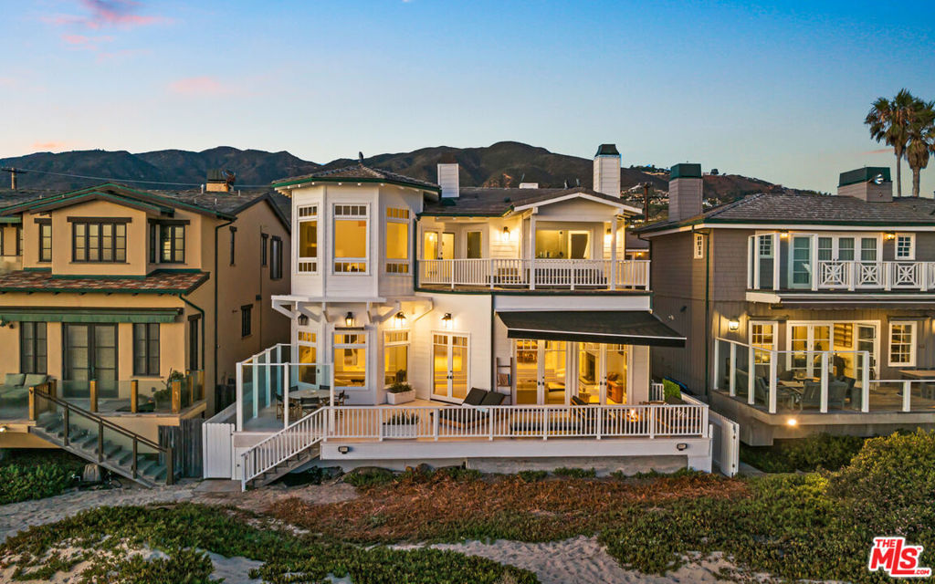 This Cape Cod-style home on Trancas Beach blends Malibu's coastline with effortless, luxurious living. Set on a wide, flat stretch of sandy shoreline, this residence offers expansive ocean views and ample space for indoor-outdoor living and entertaining. A gated entry opens to a charming breezeway, leading to a private courtyard featuring a flagstone fireplace, lounge seating, and a covered Jacuzzi with a waterfall.Freshly updated inside and out, the property includes a two-bedroom, one-bath guesthouse with its own kitchen, gym area, living room with fireplace, and abundant natural light. Accessible either from within the main house or through a separate courtyard entrance, the guesthouse offers privacy and flexibility for visitors or extended stays.The main house showcases light-toned wood floors and ocean views from the moment you step inside. Off the entry, a bonus/media room is equipped with a pool table, Stewart projection screen, en-suite bathroom, and French doors opening to the courtyard. A powder room and laundry room are also conveniently located off the entry hall.The country-style kitchen is the heart of the home, featuring a cozy fireplace, stone countertops, high-end appliances, and ample cabinet space. The kitchen connects to both the family room, which opens to the courtyard, and the living room, where ocean views take center stage. The living room boasts a fireplace and three sets of French doors that lead to a newly renovated, heated beachfront deck. This outdoor space is perfect for dining, lounging, and entertaining, complete with a Weber barbecue, firepit, and steps down to the sandy beach.An additional bar-lounge area enhances the living room's appeal, while the formal dining room, with its fireplace, flatscreen TV, and ocean views, offers a sophisticated setting for meals. A large double-sided fish tank, visible from both the dining room and hallway, adds a unique touch.The upper floor houses three bedrooms, each with balcony access. The primary suite is a luxurious retreat with vaulted ceilings, a fireplace, a sitting area with stunning ocean views, custom closets, a spa-style bath, and an oceanfront balcony with seating. Both the main house and the guesthouse are air-conditioned for comfort.Additional features include an outdoor shower in the side yard, three garages facing the street, and easy access to Trancas Country Market, a short walk away with its shops and dining options. This oceanfront getaway epitomizes Malibu living, with its perfect blend of style, comfort, and breathtaking views.