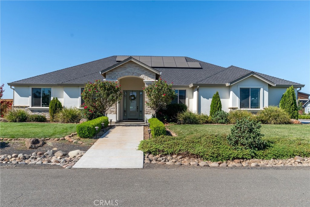 Located on the desirable North side of town, this beautiful newer-built home offers the perfect blend of peaceful living and convenience—just minutes from town, yet in a serene setting where the sunsets are absolutely breathtaking. Sitting on nearly an acre, the home’s interior is equally impressive, featuring high ceilings, crown molding, plantation shutters, gorgeous plank flooring, and abundant natural light. Off the entry, you’ll find a versatile formal dining room—perfect as an office or additional living space. The spacious living room showcases soaring ceilings, a cozy fireplace, and large windows framing picturesque backyard views. The kitchen is open to the living room, offering a peninsula with bar seating, granite countertops, custom dark wood cabinetry, subway tile backsplash, stainless steel appliances, a pantry, and a 6-burner gas cooktop. Just off the kitchen, the dining nook overlooks the sparkling pool with waterfall. This side of the home also includes the laundry room, a guest bedroom, a full bathroom, and a 3-car garage. On the opposite wing, you’ll find two additional guest bedrooms, another full bathroom, and the luxurious primary suite—complete with a spa-like ensuite featuring a walk-in shower, jetted soaking tub, and a large walk-in closet. Additional upgrades include owned solar and a whole house fan. The backyard is nothing short of spectacular—an entertainer’s dream! Enjoy a saltwater pebble tec pool, multiple lounge areas, a mini golf course, bocce ball court, pickleball court, sand volleyball court, basketball court, and a grass area complete with a 70x100 football field and goal posts—all set within beautifully landscaped grounds. This home truly has it all—style, space, and unmatched amenities—making it the perfect place to relax, entertain, and enjoy life to the fullest.