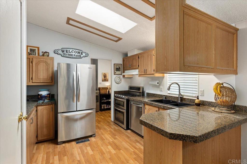 Charming 3-Bedroom Home located in a 55+ Resident-Owned Community! Welcome to Corona Del Vista, a well-maintained, resident-owned co-op share 55+ community where you own your land—no space rent or monthly land lease! This beautifully upgraded home offers a desirable split-bedroom floor plan, providing privacy between the Primary Suite and two Guest Bedrooms. This lovely home shows pride of ownership and boasts many recent upgrades and special features including a *newer A/C & ductwork, * upgraded matching granite counter tops in the Kitchen and Bathrooms, *newer black Kitchen sink and faucet for a modern touch, *double convection oven, *many upgrades in both bathrooms including new elongated toilets, *vaulted ceilings, *4 ceiling fans, plantation shutters in the Living and Dining room, built-in speakers in the Living room, *an enclosed California Room that offers additional usable space not listed in the square footage that is perfect for hobbies, storage, or recreation. Some furniture and art decor can be included and / or purchased for an additional price. Enjoy a large private yard featuring a patio and two storage sheds—one with electricity & a workbench. Plus, pick fresh fruit from your own three orange trees, one lemon tree, and an avocado tree! Corona Del Vista allows one pet under 40 lbs per household. The second resident can be age 45+. Low HOA fee of only $219.50/mo includes Trash & Dish Network Cable TV. Amenities include a clubhouse, pool, spa, library, shuffle board, BBQs, fenced dog park, RV parking (for an additional fee and per availability), and so much more! Located near shopping, restaurants, public transportation and just a short drive to the beach!