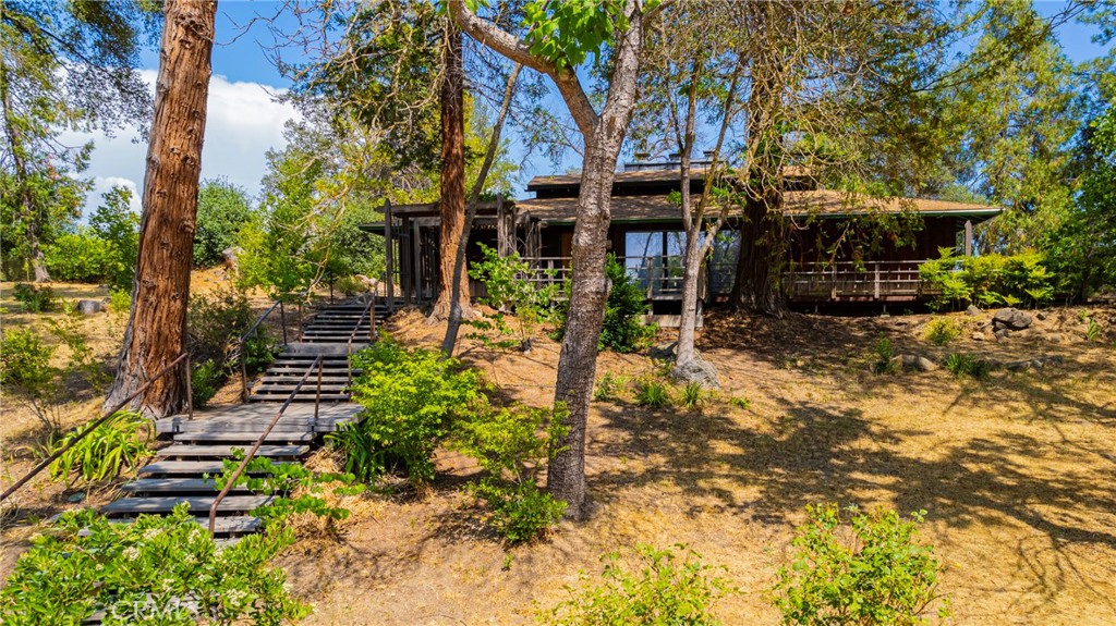 A Timeless Masterpiece Inspired by Nature and Design: Step into a truly one-of-a-kind home, lovingly designed and handcrafted by the original owners with inspiration drawn from the iconic works of Frank Lloyd Wright. This architectural gem beautifully blends natural materials, thoughtful design, and timeless craftsmanship to create a warm and welcoming living experience. The heart of the home is anchored by a striking black slate fireplace, not only a statement feature but a functional divider that eliminates the need for hallways, creating a flowing open-concept layout. Above, the pagoda-style roof and clerestory windows bring in gentle natural light while honoring Asian influences. Massive decorative chains serve as both structural support and striking visual elements, embodying the philosophy that form follows function. Inside, you’ll find a rich variety of authentic wood finishes—from Bruce oak flooring to cherry, ash, walnut, English elm, and clear redwood paneling—each thoughtfully selected and sourced from Georgia Pacific. Acoustic ceiling tiles throughout enhance both the peaceful ambiance and the entertaining potential of the home. Designed in the late 1960s, this home features an ingenious passive cooling system, eliminating the need for air conditioning. Open the screened doors and windows at night to draw in cool air, then close them by day and let the natural thermal properties of the fireplace and stone keep the home comfortably cool. Car enthusiasts and hobbyists will love the expansive four-car garage in the back, complete with a toolroom, grease pit, and paint booth—a dream workspace. The original garage, once a cozy temporary residence, now serves as a charming and functional extension of the property. Energy efficiency continues with a 10kWh solar system paired w/an automatic backup generator, powerful enough to run the entire home, including the private well. Located in one of Mariposa County’s best water regions, the strong well supports the stunning, lush landscaping lovingly created by original homeowner. Her green thumb is evident in the array of flowering plants, shade trees, and unique species not typically found in the area—made possible by the property's water supply. From the carefully chosen materials to the intentional design and self-sufficient systems, every corner of this home reflects passion, precision, and pride, this is more than a home—it's a legacy.