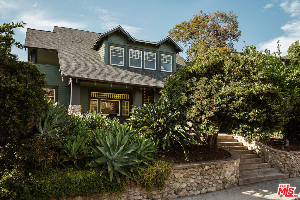 Perched above the street, beyond a stunning stone wall and lush plants, sits this meticulously reimagined 1906 Craftsman in historic Angelino Heights. This soulful 4 bedroom, 3.5 bath property perfectly blends historic craftsmanship with modern livability, and offers significant property tax savings through its Mills Act designation. Upon entering the home's beautifully landscaped grounds, you are welcomed by an expansive front porch that looks out to a large front garden. Step inside to find the elegant foyer, spacious living room, and a vibrant adjoining sunroom with walls of windows. The impeccably renovated kitchen is a chef's dream, featuring Thermador and Bosch appliances, a sprawling center island, ample counter and cabinet space, and seamless access to the home's generous dining room and magical backyard, the perfect spaces to host gatherings with family and friends. A lovely guest bedroom, full guest bathroom, and powder room complete the main floor. Upstairs you'll find an impressive primary suite with a huge walk-in closet and en-suite bathroom with spa-like shower, double vanity, and private sleeping porch with city views. Two well-appointed guest bedrooms, one of which features its own terrace that provides access to the backyard, share a perfectly updated guest bathroom. Set on a street-to-street lot, this trophy property offers a detached two-car EV-ready garage as well as multiple outdoor spaces for relaxation and play, including a heated pool/spa with surrounding lounge deck and privacy hedge, a grassy backyard, a flagstone patio with a barbecue area and built-in fire pit, a raised edible garden bed, and a variety of trees including lemon and fig. Fully renovated in 2024, this home features new hardwood floors downstairs, restored original hardwood floors upstairs, restored original windows throughout, newer appliances, and newer dual-zone HVAC. Tucked away in one of the Eastside's most coveted neighborhoods while still in close proximity to all of the incredible shops and restaurants that Echo Park and nearby neighborhoods have to offer, as well as Echo Park Lake, Dodger Stadium, Downtown LA, and more. This architectural gem is an oasis in the city.
