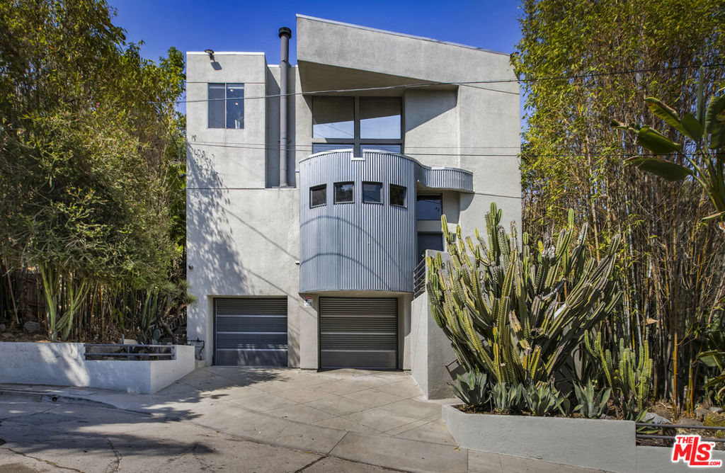 Originally designed and built in 1991 by A. Kiyohara, Moffitt & Shaver as an Architectural Showcase, this one-of-a-kind home combines striking industrial style with sustainable living. From its solid, mindful construction and low carbon footprint, to its drought-tolerant landscaping of cacti and native vegetation, the property reflects a commitment to both design and eco-consciousness. Inside, the open-concept living area features soaring ceilings, exposed ductwork, a custom fireplace, a built-in 5.1 surround sound system, and unique lighted ceiling fans. Entertain with ease thanks to GraficEye and Lutron lighting controls, a built-in bar, and a seamless flow into the dining space. The chef's kitchen is a true showpiece, boasting a Garland six-burner stove, a commercial-grade Traulsen refrigerator with a glass door, stainless steel and glass cabinetry, abundant storage, and a sleek breakfast nook. Beautiful wood-framed doors open to a large private patio, ideal for morning coffee or relaxed outdoor dining. Upstairs, the primary suite offers a spacious dressing room, a second fireplace, and a spa-like ensuite bathroom with LED lighting, a Kohler eight-jet soaking tub, a separate shower, and a double vanity. Sliding wood doors lead to an open-air bridge that connects to a private upper-level patio with sweeping views of DTLA-perfect for evening breezes and cocktails. A second bedroom with an adjacent guest bath provides comfort and flexibility. With its Murphy-style pull-down bed, it easily doubles as a home office. The home also includes a versatile flex space, ideal as an office, gym, or recording studio, along with direct access to the two-car garage, which offers additional storage and driveway parking. Located on a quiet cul-de-sac in the heart of Silver Lake, this unique industrial-inspired residence enjoys a high walk score and is just moments from scenic parks, the Silver Lake Reservoir, and an eclectic mix of local restaurants and shops.