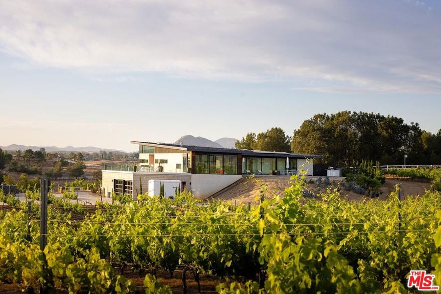 An incredible modern architectural home with income producing vineyard, in the heart of Temecula Wine Country. The Kite House, designed by Southern California-based architecture firm, Architects Magnus, was built using fire resistant hybrid construction methods with a high strength steel frame, and sustainability in mind with a standing seam metal roof under a 10kw solar system. All of the interior fixtures and appliances are premium quality and mostly imported; from the commercial grade aluminum door frames with solid core door panels, skylights, Duravit bathroom cabinets, and ORTAL tunnel fireplace (all imported from Germany), the faucet hardware is Hans Grohe, and the kitchen is all Miele (combo / steam oven, built-in coffee machine, fridge, dishwater and induction cooktop). The kitchen countertops are custom no-seam Silestone, made in Italy. The hydronic a/c system is custom made from the Italian company, Messana. Throughout the home you find Lutron lighting, and each bedroom has a commercial grade lift & slide door and window system from Reynaers, designed in Belgium. Head outside to the Pentair mineral pool and jacuzzi with propane and electric heater, and low voltage landscape lighting on photocell. Everything from the coffee machine, a/c system, lighting and pool systems can all be controlled via an app. And then of course you are surrounded by your own vineyard, 'Moto Vino' (valued as a $600k+ business, conveying with the sale of the home) that was developed by Drake Enterprises of Temecula, utilizing efficient machine harvesting and is fully OSHA compliant with service roads, filter station and drip irrigation (3.3 acres of Syrah, and 0.5 acres of Grenache Blanc vineyard that generates $40-$50k in revenue/year for another projected 20+ years). This is an incredibly unique offering of Southern California modern architecture meets vineyard that was planned and developed in-tandem to maximize the 4.88 acre properties view orientation, grape yields and functionality.