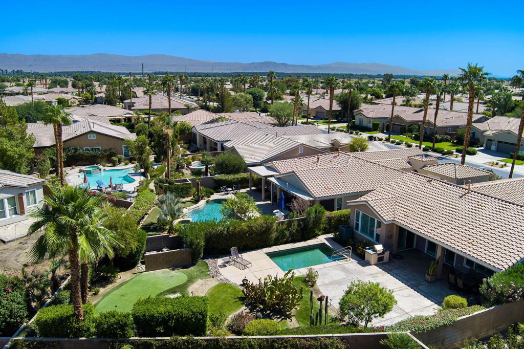 Situated within the prestigious 55+ gated community of Trilogy La Quinta, this impeccably maintained Oasis floor plan offers an exceptional blend of refined interior living and vibrant outdoor lifestyle. Sited on an expansive 9,000 square foot lot, the residence features approximately 1,580 square feet of thoughtfully designed living space, encompassing 2 spacious bedrooms and 2 well-appointed bathrooms. Enter through a custom etched glass front door into a light-filled great room enhanced by a built-in media and entertainment center, elegant plantation shutters, and a seamless flow into the adjacent dining area with a dedicated hutch niche. The gourmet kitchen is adorned with granite countertops, upgraded cabinetry, a central prep island, built-in microwave, gas range and oven, dishwasher, and a generously sized walk-in pantry--perfect for entertaining or everyday culinary pursuits. The private primary suite showcases a bay window with views of the backyard, direct access via sliding glass doors, and an en suite bathroom complete with dual vanities, tiled countertops, a walk-in shower, and a spacious walk-in closet. Designed for year-round enjoyment, the resort-style backyard is a true entertainer's dream--featuring a rectangular Pebble Tec pool, an extended patio cover, built-in BBQ station, concrete deck, and a professionally installed PGA-style putting green. This remarkable property offers both comfort and luxury in one of the desert's most sought-after active adult communities. A must-see for discerning buyers--schedule your private showing today.