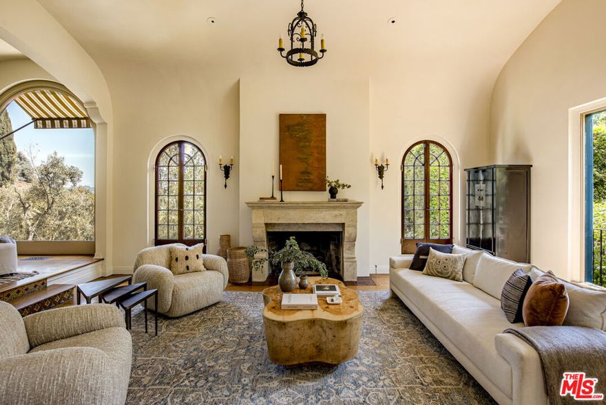 Perched on a coveted private corner lot in the heart of Los Feliz, Villa Palazzetto is a rare offering -- an exquisitely preserved 1925 Mediterranean estate with rich Hollywood history and timeless elegance. Formerly home to legendary director and screenwriter Delmer Daves, this walled and gated compound blends grandeur, privacy, and charm just moments from Griffith Park, the Greek Theatre, and all the vibrant shops and restaurants of Los Feliz Village. From the moment you enter the soaring two-story foyer, the home's scale is undeniable. Grand rooms with high ceilings, architectural detailing, and sweeping staircases set the tone. The living room, anchored by a French stone fireplace, captures expansive views of Downtown Los Angeles, while the formal dining room and library offer both sophistication and warmth.The chef's kitchen is outfitted with a center island and breakfast area, opening to a media room that flows seamlessly to the outdoors, where a heated dining pavilion, an outdoor kitchen with built-in BBQ, and a resort-style saltwater pool and jacuzzi await. Finished in stunning mosaic tile and surrounded by mature trees and lush landscaping, the backyard is as functional as it is beautiful.Upstairs, the primary suite is a sanctuary unto itself complete with a fireplace, a walk-in closet, a spa-like bathroom with heated floors, and breathtaking views. Two additional ensuite guest rooms also enjoy privacy and stunning vistas. The lower level features a guest or mother-in-law suite with its own private entrance and three bedrooms, thoughtfully situated two floors below the primary -- an invaluable layout for households that regularly host extended family or long-term guests.Among the home's other cherished features are a top-of-the-line dual-fuel Generac generator, abundant storage throughout, and even a charming original laundry chute -- a detail the current owners lovingly admit they'll miss most. Located directly across from the Berendo Stairs, one of Los Angeles's storied "secret staircases," the property enjoys a rare combination of historic charm, architectural drama, and modern comfort. Majestic, romantic, and steeped in legacy, Villa Palazzetto is a true Los Feliz treasure offering the serenity of a private hillside estate with the heartbeat of the city just outside your door.