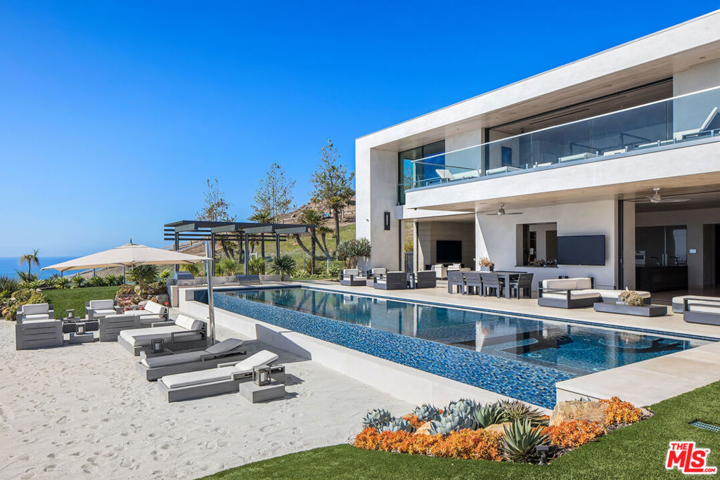 VILLA SPLENDIDO, as featured in the WSJ, is perched high on the hillside, where land embraces the sea, overlooking the renowned "Billionaire's Beach." This fully-furnished masterpiece, envisioned by acclaimed architect Doug Burdge (AIA), embodies sophistication and contemporary flair. Accessed via a private drive off PCH, this exclusive estate boasts a dual-gated entrance, revealing a lush tropical sanctuary spanning on approximately 17 acres of meticulously manicured grounds. A radiant driveway sets the scene for a grand arrival, leading to a front entrance that unveils breathtaking 180-degree ocean views, capturing the essence of quintessential Malibu living from sunrise to sunset. This state-of-the-art residence features an extensive wellness center, encompassing a private gym, massage room, adjoining steam/sauna, and an indoor jacuzzi adorned with overhead skylights. The chef's kitchen, complete with premium appliances, enhances culinary endeavors. Additionally, the estate offers an elevator, private office, separate guest house, infinity pool with a swim up bar, outdoor pizza oven, and an entertainment enclave with a bar reminiscent of a boutique hotel. VILLA SPLENDIDO beckons you to savor the pinnacle of luxury living, where architectural brilliance meets coastal elegance, delivering an unparalleled lifestyle experience in the heart of Malibu. Available to be sold as a package.
