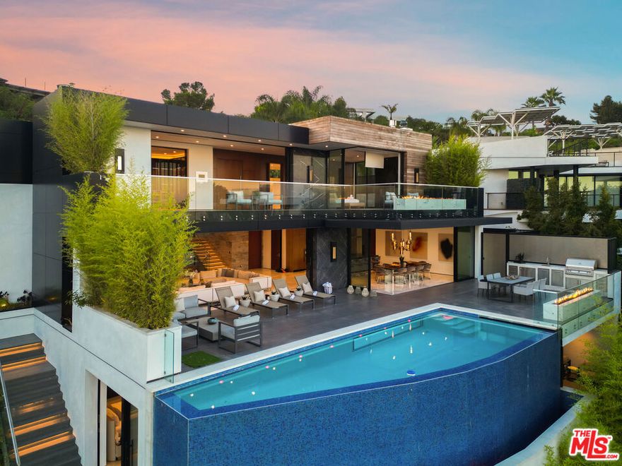 A rare architectural triumph, this estate exudes timeless sophistication and contemporary grace at every turn. From the moment you enter through the grand entry, you are immersed in a private realm of design excellence and tranquil opulence. Perfectly positioned in the prestigious Bird Streets of the Hollywood Hills, this modern showpiece showcases sweeping city and ocean views. Conceived by renowned architect Ameen Ayoub, the residence harmonizes bold modern architecture with inviting warmth achieving a seamless fusion of innovation and livability. Every element reflects masterful attention to detail. The gourmet kitchen is equipped with Miele appliances and refined bespoke finishes. Entertain in style beside the dramatic aquarium bar and infinity-edge pool, or display your collection in the striking honeycomb quartz wine gallery. Additional amenities include a sound-isolated theater, showcase garage, and a fully equipped wellness studio with sauna and steam shower. The primary suite offers an atmosphere of calm sophistication, featuring a statement fireplace, private terrace, dual spa-inspired baths, and a couture-quality dressing room. More than a residence, this property defines a lifestyle an expression of modern artistry, elevated comfort, and the quintessential Los Angeles experience.