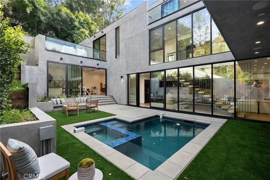 Tucked away in the hills of Studio City on a secluded cul-de-sac, resides this new-construction architectural gem that offers dramatic views of the Valley. A sleek, modern exterior welcomes you into a warm interior filled with natural woods, imported stone and expansive walls of glass that bathe the space in natural light. Thoughtfully designed for both everyday living and entertaining, the open-concept layout is anchored by a spacious family room that flows seamlessly into a gourmet chef’s kitchen equipped with top-of-the-line Miele appliances, an oversized island with seating and walk-in pantry. Slide open the floor-to-ceiling glass doors and step out to your sun-drenched central courtyard – complete with a sparkling pool/spa, cozy built-in fire pit and ample space for lounging or enjoying an al fresco meal. Rounding out the main level is an inviting living room, formal dining room and chic powder bathroom. A sleek floating staircase leads you upstairs, where you’ll find four generously sized ensuite bedrooms, including an impressive primary suite that features a private patio, custom walk-in closet and sumptuous bathroom, boasting a soaking tub, rainfall shower and dual vanities. Up another level, there’s a bonus room with a wet bar and full bathroom that opens to an expansive rooftop terrace, offering breathtaking vistas of the Valley – perfect for entertaining or relaxing while you watch the sunset. Additional highlights include a lower-level ensuite bedroom, laundry room, high ceilings throughout, smart home features like integrated speakers, a state-of-the-art security system and three-car garage. Ideally located South of the Boulevard within the top-rated Carpenter School District, this exceptional property is just moments away from trendy restaurants, boutique shops, Fryman Canyon hiking trails and so much more. This is modern luxury living at its finest!