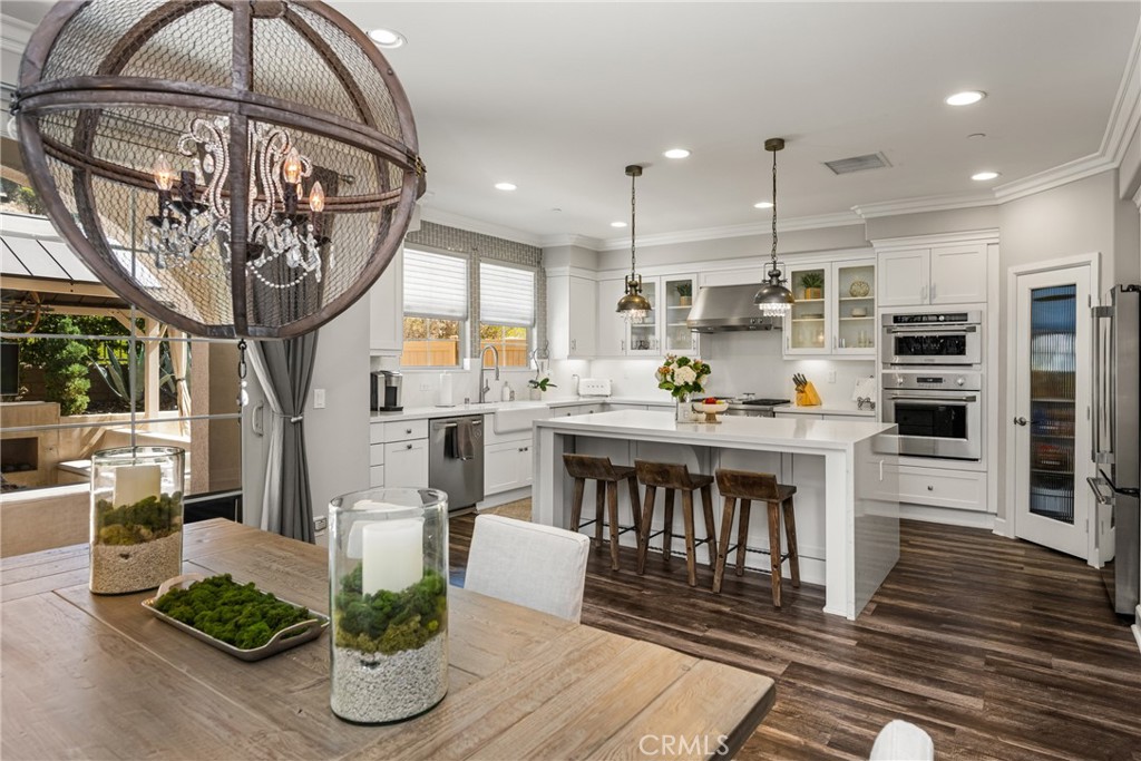 Welcome to your dream townhome in Yorba Linda! This stunning residence truly rivals any model home with designer finishes, custom craftsmanship and nearly $350,000 in upgrades. From the moment you enter, the high ceilings, wide staircases, and open floor plan create a grand yet inviting feel. Throughout the home, you’ll find engineered wood flooring that blends durability with warmth, perfectly complementing the custom paint palette, plantation shutters and designer lighting choices that have been selected with care.
At the heart of the home is a chef’s kitchen featuring professional-grade appliances, quartz countertops, and an oversized island with a waterfall edge. The kitchen is open to a large dining room, enhanced with elegant wainscoting that adds both charm and character. For wine enthusiasts, a custom wine closet with backlighting and a glass door offers a touch of luxury and becomes an instant conversation piece.
One of the home’s standout features is the seamless connection to its outdoor spaces. Off the dining room, sliding doors lead to one of the largest yards in the community—a rare find for townhome living. This private oasis backs up to a lush hillside, providing greenery and a sense of seclusion that enhances your everyday retreat.
The yard has been thoughtfully designed with an intimate seating area, perfect for quiet evenings or gatherings with friends. A custom fireplace and a new patio cover make the space both inviting and functional year-round. Whether you’re hosting a summer barbecue or relaxing under the stars, this backyard delivers.
The spacious living room is anchored by a custom shiplap wall with built-ins, a cozy fireplace, and access to a balcony with views. Upstairs, the primary suite impresses with mountain views, a walk-in closet, and a spa-like bath with dual vanities, soaking tub, and walk-in shower. Secondary bedrooms feature mirrored closets, with one offering sleek zebra wood built-ins.
Car lovers will appreciate the oversized 4-car garage with separate A/C unit, epoxy floors, custom cabinetry, workbench, LED lighting, and vertical lift opener. The home also features smart technology, home audio, and security system, throughout.
Set in a highly desirable community, residents enjoy resort-style amenities including a pool, spa, gym, playground, BBQs, and clubhouse. With its premium lot, extensive upgrades, and unmatched style, this 3-bedroom, 2.5-bath home is a true showstopper you won’t want to miss!