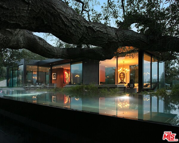 The internationally praised Oak Pass House consists of 6 bedroom and 10 bathrooms sited over 3.5 whimsical acres. THIS architectural masterpiece designed by AIA Award winning ARCHITECT Noah Walker embraces its unique hillside topography, featuring an "upside down" program with main living spaces above and all bedrooms below. The 8000 sq ft main house is sculpted into the hillside surrounded by over 130 majestic, live oak trees. positioned below meandering branches of one of the largest Oaks on the property sits a 75 foot lap pool with infinity edges. Panoramic canyon views appear from nearly every window and angle. The walnut, marble, and polished concrete finishings throughout provides a stunning organic ambiance while fully pocketed window walls create an indoor/outdoor feel. Further up the canopied driveway, the separate guest house with two en suite bedrooms and full CHEFS kitchen, was thoughtfully designed for live concerts and entertaining.