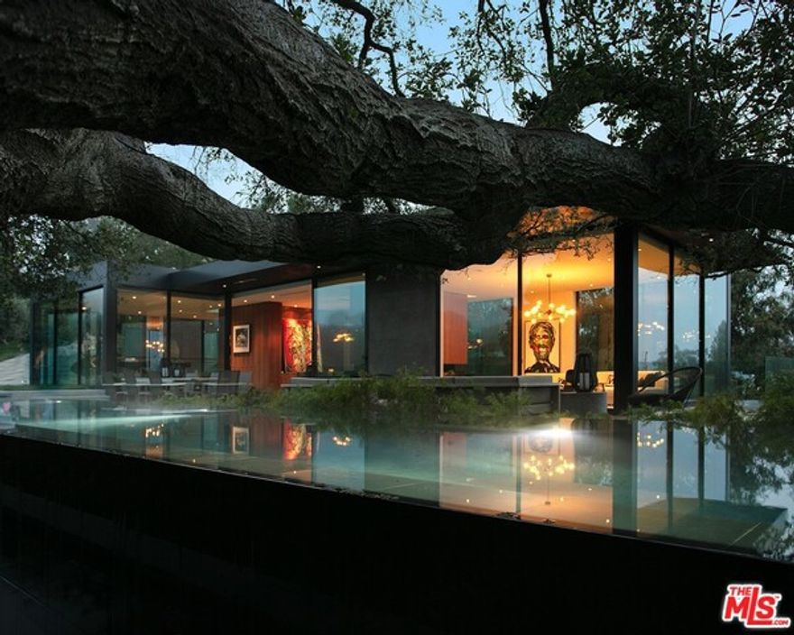 The internationally praised Oak Pass House consists of  6 bedroom and 10 bathrooms sited over 3.5 whimsical acres. THIS architectural masterpiece designed by AIA Award winning ARCHITECT Noah Walker embraces its unique hillside topography, featuring an "upside down" program with main living spaces above and all bedrooms below. The 8000 sq ft  main house is sculpted into the hillside surrounded by over 130 majestic, live oak trees. positioned below meandering branches of one of the largest Oaks on the property sits a 75 foot lap pool with infinity edges. Panoramic canyon views appear from nearly every window and angle. The walnut, marble, and polished concrete finishings throughout provides a stunning organic ambiance while fully pocketed window walls create an indoor/outdoor feel. Further up the canopied driveway, the separate guest house with two en suite bedrooms and full CHEFS kitchen, was thoughtfully designed for live concerts and entertaining.