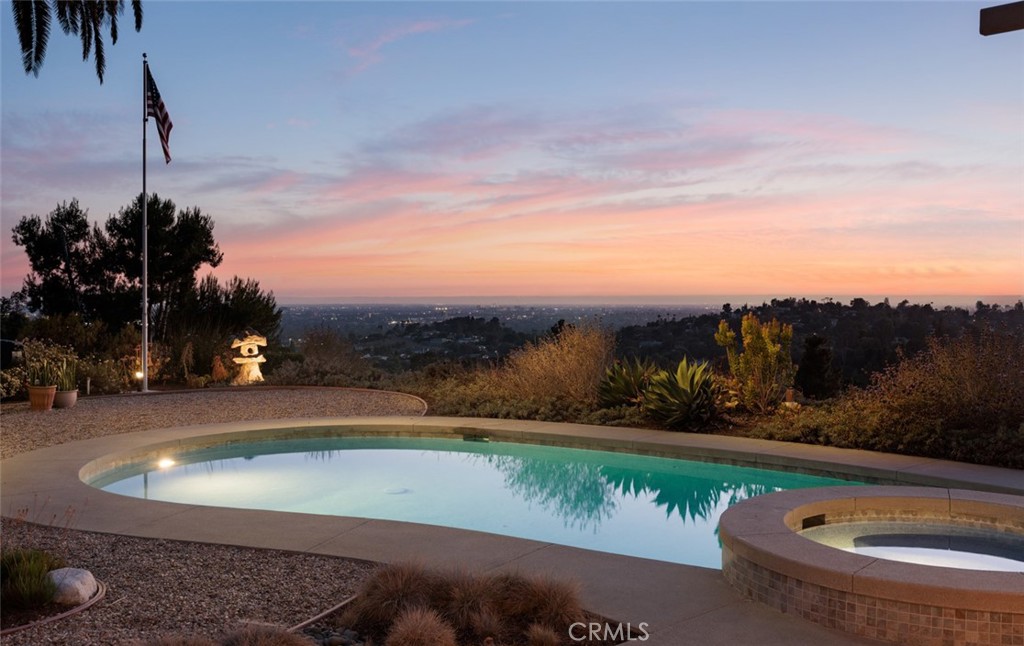 ARCHITECTURAL HILLTOP RETREAT | PANORAMIC VIEWS | REBUILT CUSTOM HOME | NORTH TUSTIN SANCTUARY | Perched high above North Tustin on a premium 32,670 sq ft lot, 10551 Hillsboro Road offers a rare blend of architectural design, peaceful privacy, and breathtaking views that stretch from Catalina Island to the LA skyline. Reimagined from the ground up in 2017, this single-level, 3-bedroom, 2.5-bathroom custom home was thoughtfully rebuilt to the highest standards, with only a portion of the original framing retained—reinforced with steel and brought fully up to modern code. The home’s layout was designed by an architect with both beauty and function in mind. Wide doorways, a wheelchair-accessible ensuite, and an open concept floorplan make it ideal for long-term livability. Smooth-finish walls, porcelain tile flooring throughout, solid core doors, 5/8" drywall, and expansive Kolbe metal-clad windows create a seamless, modern aesthetic that floods the home with light while preserving privacy and quiet. Every room offers a sense of calm, connection to the outdoors, and unmatched sunset and city-light views. The chef’s kitchen opens effortlessly into the dining and living areas, while motorized Hunter Douglas shades and a whole-house ELK M1 smart system provide luxury-level comfort and convenience. The rebuilt pool and new spa are framed by a steel patio cover with motorized shade, offering year-round enjoyment in your own secluded backyard haven. Two separate air conditioning units ensure personalized climate control throughout the home. Outdoors, the grounds are as intentional as the interior. Native plantings, fire-conscious landscaping, a private fruit orchard, and master-valve-controlled drip irrigation provide beauty and function with low maintenance in mind. An underground drainage system leads to the sewer, and all utilities are underground for a clean, unobstructed landscape. A 20-foot flagpole, collectible Japanese toro lanterns, and mature trees bring elegance and character to the expansive yard. This is more than a home—it’s a retreat, a legacy, and a place of peace. Lovingly cared for and deeply appreciated, 10551 Hillsboro Road is ready to welcome its next steward. Come experience one of North Tustin’s most serene and inspiring properties.