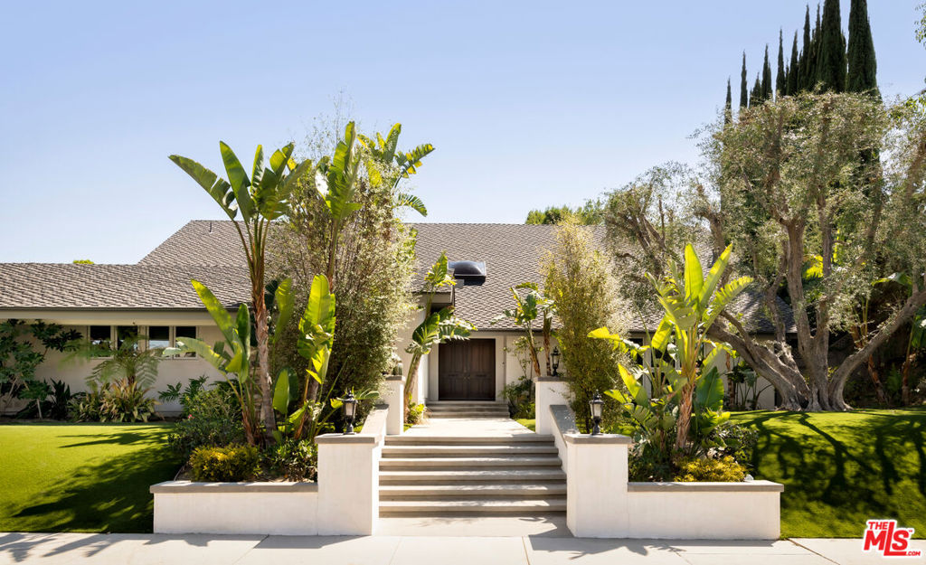 Where sleek Mid-Century design meets modern elegance, this turnkey Tarzana residence rests on a generous 17,000 SF lot within one of the neighborhood's most coveted enclaves. Set on a rare, flat cul-de-sac, the home offers a secluded sanctuary surrounded by lush landscaping and exceptional privacy. Spanning 4,424 SF, the two-level residence features 5 bedrooms, including a main-level primary suite and an upper-level primary retreat, along with an office, gym, and 5 bathrooms all thoughtfully designed for both comfort and style. The main level welcomes you with soaring ceilings and spacious living areas, including two additional bedrooms, a formal living room, dining room with a dedicated pantry for china and silver, family room with built-in bar, gourmet kitchen with Viking and Sub-Zero appliances, and a guest or staff suite. French doors open to a private backyard oasis complete with a heated pool and spa, built-in BBQ, and multiple dining and lounging areas. Upstairs, the upper-level primary retreat occupies the entire floor, featuring a charming fireplace, balcony with resort-like views of the grounds and mountains, and a spa-inspired ensuite with a soaking tub, steam shower, walk-in closet, and versatile spaces for an office, media room, gym, and more. Combining iconic Mid-Century design, modern finishes, and unparalleled indoor-outdoor living, this residence offers an exclusive opportunity to enjoy timeless elegance in one of the Valley's most sought-after neighborhoods.