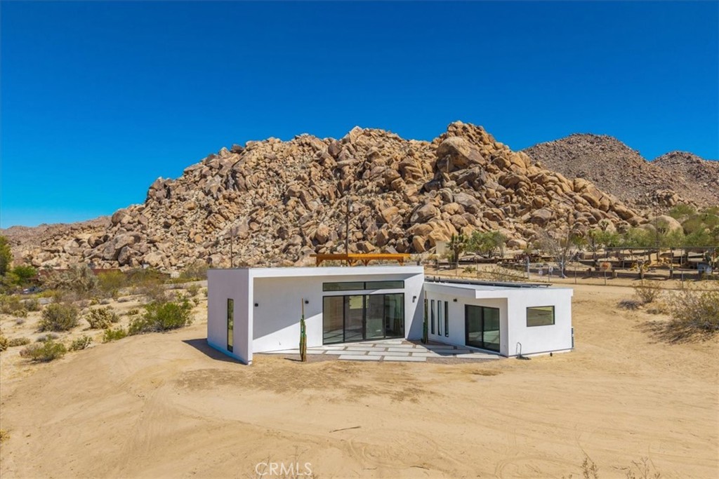 Spectacular New Construction Design & Location: Walking distance to Joshua Tree National Park – leave car at home and hike or jog into the vast wilderness only minutes away. In addition to the close proximity of nature, and only one parcel away, stands Joshua Tree’s most significant architectural jewel – The Kellogg Doolittle House, built into the boulders. Few local properties can boast such an iconic neighborhood structure and the freedom to roam at will on protected land. Sited at the base of a boulder mountain sits this beautifully designed home with a sunken living room, polished concrete floors, clean lines and numerous windows with stunning views in every direction. The kitchen features an island with double-waterfall quartz counters, subway tile backsplash and a window above the sink that perfectly frames the boulders above. Zoned ductless mini-splits allows for efficient cooling and heating. Floor-to-ceiling tile in the bathroom. Each bedroom has its own large sliding glass door for indoor/outdoor living. This is the second home the owners have built in prestigious Panorama Heights in South Joshua Tree. The first home is a high-grossing Airbnb that was featured in Architectural Digest, with a similar L-shaped design. However, this new property features a more spectacular and coveted location. Views to the west include SoCal’s tallest mountain – San Gorgonio – and sublime sunsets. No through traffic, as road ends only a few away near the National Park boundary. Also included are plans for a pool that are pending approval (for buyer to build at a later date if desired.) Whether looking for a primary residence or a vacation home investment, few properties share the qualities of this unique home and location.