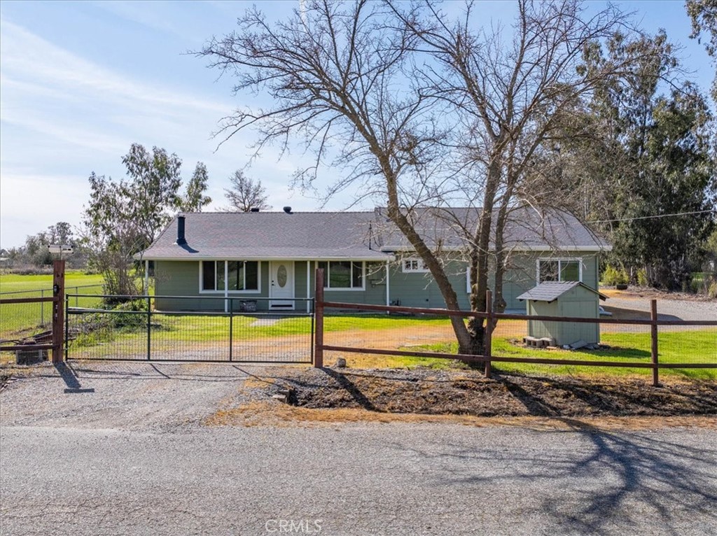 Tucked away on almost an acre fully fenced, this warm and welcoming 3-bedroom, 2-bath home is designed for comfortable living. Drive through the electric gate and take a step inside. You’ll notice the open and airy feel, enhanced by luxury vinyl plank floors, an abundance of sunlight streaming through large windows, and an oversized living space anchored by a freestanding wood stove with an attractive brick backdrop. The kitchen is thoughtfully designed for both everyday living and entertaining. Bright white cabinets, sleek quartz counters, and an electric range offer a clean, modern touch, while the adjacent dining nook makes serving meals effortless. Your private primary suite is a true escape, featuring direct access to the backyard, two spacious walk-in closets, and a spa-like bath complete with dual sinks, plentiful cabinetry, tile flooring, and an impressive walk-in shower wrapped in tile. Practical perks include an indoor laundry room with storage, two comfortable guest bedrooms, linen storage, and ceiling fans in multiple rooms. Outside, you’ll find a detached two-car garage with an additional storage bay, a storage shed, and a covered patio ideal for gatherings or lazy afternoons. With a peaceful setting, generous lot size, and a long list of features, this home offers the perfect blend of country charm and modern convenience.