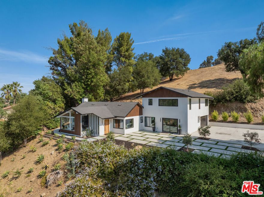 From the moment the automated gates open, The Sky Estate at 9425 Gierson feels less like a residence and more like a private retreat in the clouds. A sculpted drive winds past a detached four car garage and curated California modern landscaping of olive and willow trees, specimen succulents, and native cacti. As you ascend the ridge, the city fades away and the horizon opens wide. Inside, a dramatic living room with 12-foot ceilings and floor to ceiling glass frames panoramic mountain and valley vistas turning every sunset into part of the decor. Wide plank oak floors lead into an open dining area and chef's kitchen with Italian cabinetry, a quartz waterfall island, and a complete Thermador suite, designed for effortless entertaining and everyday comfort. The main level also offers a junior en-suite for guests or multigenerational living, a powder bath, mudroom, laundry, and a lounge with canyon views. Floating Brazilian stairs rise to two secondary bedrooms and a breathtaking primary suite, where mornings begin with sunrise over the ridgeline. The spa inspired bath showcases a freestanding tub, dual rain showers, and custom wardrobe storage. Outdoors, the estate unfolds like a hillside resort: a pool with built-in BBQ, a putting green, and a sky-deck with firepit capturing 270-degree city-light views. With nearly two acres of LARA-zoned land, the property also carries rare equestrian-friendly allowances an uncommon advantage in Los Angeles that expands the lifestyle possibilities of this private sanctuary. Thoughtfully engineered with dual-zone HVAC, tankless water heater, 400-amp service, EV charging, and Low-E glazing, The Sky Estate offers architectural presence, modern luxury, and a sense of escape ready to welcome its next chapter.