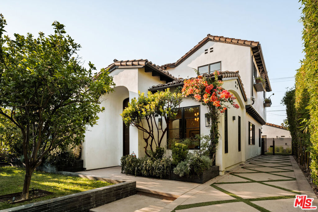 Tucked away on a coveted street in prime Beverly Grove, this Spanish inspired contemporary offers timeless character blended with modern comforts. Behind a gated entry, the 5 bedroom, 4.5 bathroom residence includes a newly built ADU ideal for guests, work from home, or additional income. A dramatic arched front door opens into a thoughtfully designed floor plan, where soaring ceilings, rich mahogany toned wood floors, and curated designer finishes echo the home's architectural roots. The formal living room features a statement fireplace, custom inlaid tile, and a storybook window that floods the space with natural light. The chef's kitchen is outfitted with Miele appliances, a marble waterfall island, and custom cabinetry, seamlessly connecting to an open-concept dining and family room. Additional luxuries include integrated speakers throughout, and a home security system. Floor to ceiling glass doors create a seamless indoor-outdoor flow to the private backyard oasis complete with a sparkling pool, spa, and lounge-ready patio. Professionally landscaped, the yard offers numerous upgrades such as custom pool lighting and recently installed safety fencing. Upstairs, the expansive primary suite offers a fireplace, private terrace with views of the Hollywood Hills, automated black-out blinds and a spa-inspired bath. Two additional upstairs bedrooms share a stylish Jack-and-Jill bath, while a guest suite downstairs offers privacy and flexibility. The ADU features a full kitchen and bathroom, ideal as a guest house, studio, or rental opportunity. Perfectly positioned in one of Los Angeles' most refined and walkable enclaves, this residence offers seamless access to nearby Melrose Avenue, The Grove, and the Beverly Center, along with a curated array of renowned restaurants, boutique shopping, and cultural landmarks. A rare offering that blends architectural character with an address defined by both elegance and ease.
