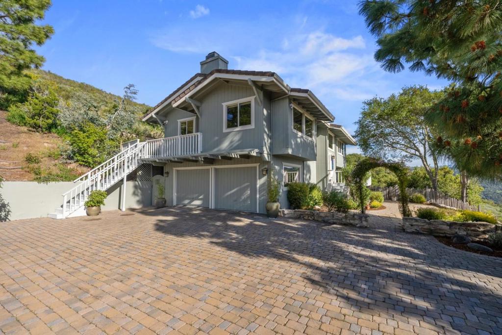 Tucked away on over two acres of idyllic serene landscape, this magical property has been thoughtfully designed to capture breathtaking panoramic views of picturesque Carmel Valley. Rolling grassy hills, magnificent oak trees and open blue skies dazzle the senses to paint a virtual plein air masterpiece. Inside you find a well-appointed home with all the comforts of modern life, including dual-pane windows, air conditioning, cherry hardwood floors and two stone fireplaces. The fabulous kitchen is equipped with granite counters and high-end stainless appliances including Sub-Zero fridge and Viking range. Retreat to your luxurious primary ensuite boasting ample closet space, dual sinks, travertine tile, separate shower and soaking tub with picture window of majestic mountains. Relax outside and entertain in the sun with Carmel stone patios, colorful gardens, spacious deck and expansive paver courtyard. A separate newer 4-car garage/workshop structure with its own driveway offers potential for conversion to ADU. The bonus art studio provides tranquil views. Enjoy the resort lifestyle of this secluded gem in the highly desirable Los Tulares neighborhood, with natural surroundings and hiking trails, just minutes from shopping, parks, restaurants and all the amenities of luxury living.
