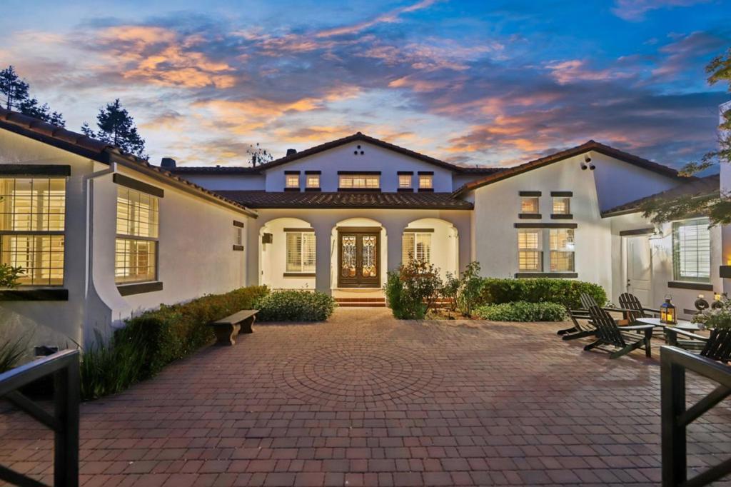 Welcome to Comstock Estates an extraordinary North San Benito County estate on 4.7 acres, designed for luxury living, multi-generational comfort, and entertaining at scale. The single-level 4,308 SF main residence offers 4 ensuite bedrooms, an office/flex room, a gourmet chefs kitchen with premium Miele and KitchenAid appliances, and a stunning wine room holding up to 1,840 bottles. Enjoy soaring vaulted ceilings, handcrafted copper sinks, custom cabinetry, and multiple indoor/outdoor fireplaces. Two additional buildings include a full 2-bed pool house with media/game room and a His & Hers flex space ideal for a gym, office, or workshop plus garages for 6+ cars. The resort-style backyard features a solar-heated pool, spa, stone bar, and 3 gazebos. Equestrian-ready with 1.5 acres of pasture, paddocks, hay storage, and a 1-acre Merlot vineyard with agricultural water. Fully fenced with electric gate, generator, and cameras. A rare opportunity to own a private, fully equipped estate with room for everything.