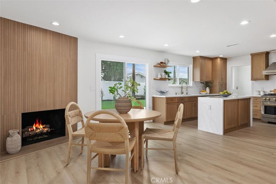 A celebration of clean lines, natural light, and thoughtful craftsmanship, this newly reimagined 1962 Mid-Century ranch-style home invites you to enjoy the best of both past and present. Situated in a charming neighborhood just minutes from Old Towne Orange, the home has been meticulously remodeled with curated finishes and elevated function—creating a space where timeless style meets today’s ease. Spanning approx. 1,469 square feet, the single-level layout flows effortlessly with four bedrooms and two baths, including a light-filled living and dining area anchored by a modern slat-wood fireplace surround. The new designer kitchen opens seamlessly to the backyard and features a dual-waterfall island, full quartz backsplash, light oak Shaker cabinetry, and high-end stainless appliances including a pro-style Zline range and drawer microwave. A spacious mudroom with laundry, cabinetry, and sink connects to the freshly finished two-car garage with epoxy floors and new door. Down the hall, secondary bedrooms are bright and functional, while the guest bath pairs timeless black-and-white tile with updated fixtures. The primary suite offers a walk-in closet and a serene ensuite with a custom vanity and walk-in shower. Throughout the home, wide-plank white oak-style LVP, recessed lighting, Shaker doors with black hardware, dual-pane windows, Nest smart thermostat, and Ring doorbell enhance both comfort and style. Outdoors, the 7,070 sq. ft. lot is equally turnkey. A new roof, fresh exterior paint, lush lawn, automatic sprinklers, and tile-finished patio come together to create a front and backyard that feel as effortless as they are inviting. Just two miles from the restaurants, galleries, and vintage charm of the Orange Circle—with easy access to parks, schools, shopping, Angel Stadium, Disneyland, and more—this is a rare opportunity to live beautifully in one of Orange County’s most cherished communities.
