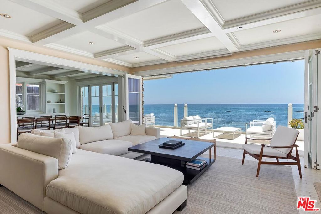 Behind the guarded gates of the legendary Malibu Colony, this East Coast-inspired coastal retreat offers a rare blend of timeless elegance and laid-back luxury. With approximately 64 feet of prime sandy frontage, this residence, designed by acclaimed architect Richard Landry, sits just 50 feet from one of the most iconic surf breaks in the world. The home captures the essence of Malibu living at its most elevated. Four en-suite bedrooms in the main house and a detached guest house are thoughtfully arranged to maximize privacy while maintaining an effortless connection to the sea. Expansive bi-folding glass doors dissolve the boundary between indoors and out, inviting in salt air and an ever-changing canvas of ocean blues. The views, arguably the best in the Colony, stretch across the shimmering coastline, framed by the curve of Surfrider Beach and the distant mountains. From the rooftop spa retreat to the open-air barbecue lounge, every detail invites celebration, reflection, and the kind of inspiration only the Pacific can provide. Just minutes from Nobu, Soho House, and the world's finest shopping and dining, this is more than a home. It is a front-row seat to the Malibu dream, offered on one of the widest beachfront lots in the Colony. An extraordinary, once-in-a-lifetime opportunity to live where luxury meets legend.