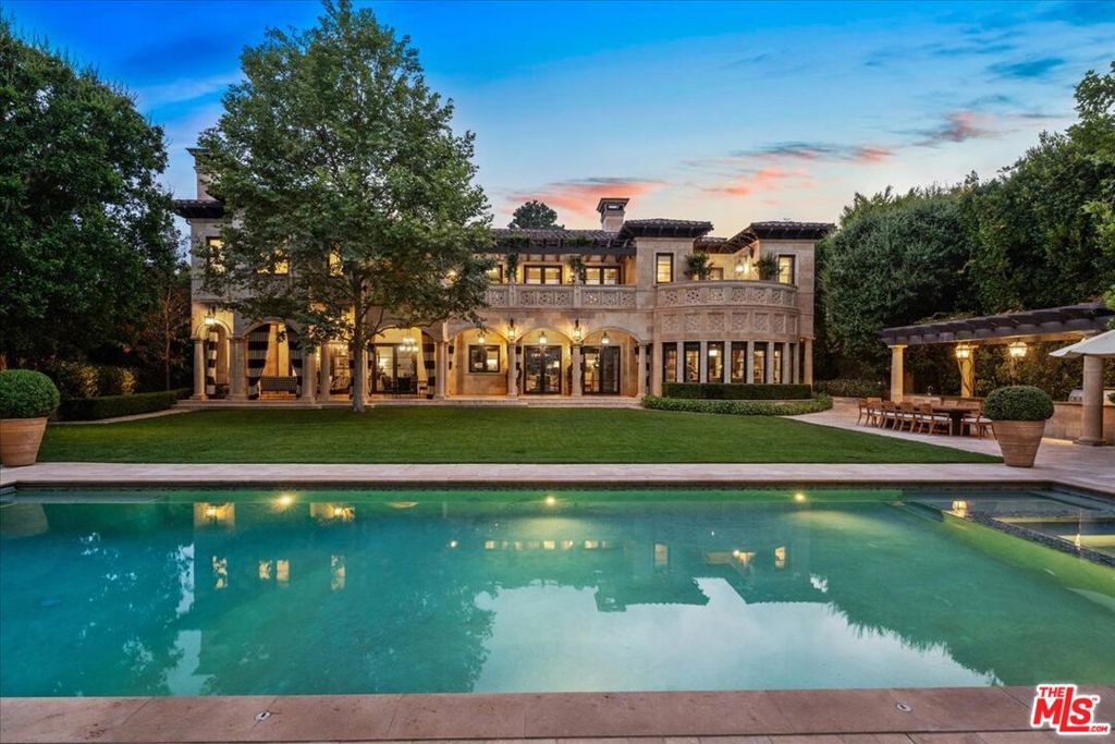 A triumph of design, craftsmanship, and grandeur, 804 N. Elm Drive is an extraordinary approx. 20,000-square-foot Italian-style limestone villa nestled in the heart of the prime Beverly Hills Flats. Created by a powerhouse team of Los Angeles design icons - architect Richard Landry, builder John Finton, interior designer Joan Behnke, and landscape designer Christine London -this 7-bedroom, 15-bathroom estate was the recipient of Robb Report's Ultimate Home Award and stands as a true modern classic. Completed in 2011, the home is crafted entirely from hand-carved Dijon limestone, with a west-facing facade that fuses classical Italian elegance with Art Deco sophistication. The interiors are a symphony of curated detail, from a soaring foyer with a 7-foot bronze chandelier and Dale Chihuly glass sculptures, to panel-lined corridors illuminated by silk runners and vintage light fixtures. Every space has been designed for both intimate living and large-scale entertaining. The grand living room features custom architectural details and opens seamlessly to a stone-paved loggia through accordion doors, allowing for effortless indoor-outdoor flow. A 1,000-gallon saltwater aquarium, a two-story groin-vaulted gallery terrace, and a theater with a hand-crafted mahogany ceiling enrich the estate's immersive ambiance. The formal dining room overlooks the front garden and features custom millwork and bespoke lighting. The kitchen, designed to accommodate multiple preparation areas, is equipped with a stainless-steel barrel-vaulted ceiling, kosher Italian granite countertops, and hand-built mahogany cabinetry. A spacious breakfast room opens to the garden, pool, and water features, emphasizing the home's seamless connection between indoor comfort and outdoor beauty. The primary suite is a private sanctuary with vaulted ceilings, French doors to a trellised terrace, dual master baths, and a flexible sitting area that can be closed off with a large pocket door. One primary bathroom features a scalloped ceiling, custom mosaic floors, and a glowing skylight, while the second primary bathroom is clad in rich wood and Italian marble with bespoke bronze fixtures. Below ground, the lower level includes a nautically inspired game room, a full spa with an Endless pool, hot tub, steam room, massage area, and a professional-grade home theater. These amenities provide space for both recreation and relaxation, all finished to the highest standards. The exterior continues the home's architectural brilliance with a limestone rear facade enhanced by classic columns, arched openings, and carved roof details. The landscaping reflects a Northern Italian palette, transitioning from formal clipped boxwood and citrus trees at the front to lush, informal plantings and potted greenery surrounding the pool and entertaining areas in the rear. A pergola with a partial outdoor kitchen and grill completes the backyard retreat. A separate stone-clad guest pavilion offers privacy and rustic charm, positioned as a counterpoint to the elegance of the main residence. 804 N. Elm Drive is a rare achievement in architectural vision, blending classical European inspiration with California luxury living in one of Beverly Hills' most coveted locations.