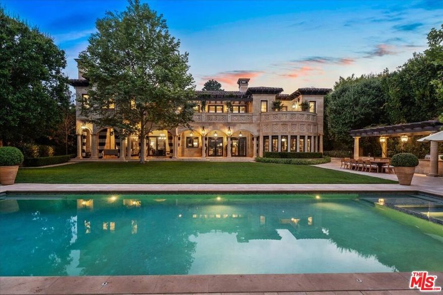 A triumph of design, craftsmanship, and grandeur, 804 N. Elm Drive is an extraordinary approx. 20,000-square-foot Italian-style limestone villa nestled in the heart of the prime Beverly Hills Flats. Created by a powerhouse team of Los Angeles design icons - architect Richard Landry, builder John Finton, interior designer Joan Behnke, and landscape designer Christine London -this 7-bedroom, 15-bathroom estate was the recipient of Robb Report's Ultimate Home Award and stands as a true modern classic. Completed in 2011, the home is crafted entirely from hand-carved Dijon limestone, with a west-facing facade that fuses classical Italian elegance with Art Deco sophistication. The interiors are a symphony of curated detail, from a soaring foyer with a 7-foot bronze chandelier and Dale Chihuly glass sculptures, to panel-lined corridors illuminated by silk runners and vintage light fixtures. Every space has been designed for both intimate living and large-scale entertaining. The grand living room features custom architectural details and opens seamlessly to a stone-paved loggia through accordion doors, allowing for effortless indoor-outdoor flow. A 1,000-gallon saltwater aquarium, a two-story groin-vaulted gallery terrace, and a theater with a hand-crafted mahogany ceiling enrich the estate's immersive ambiance. The formal dining room overlooks the front garden and features custom millwork and bespoke lighting. The kitchen, designed to accommodate multiple preparation areas, is equipped with a stainless-steel barrel-vaulted ceiling, kosher Italian granite countertops, and hand-built mahogany cabinetry. A spacious breakfast room opens to the garden, pool, and water features, emphasizing the home's seamless connection between indoor comfort and outdoor beauty. The primary suite is a private sanctuary with vaulted ceilings, French doors to a trellised terrace, dual master baths, and a flexible sitting area that can be closed off with a large pocket door. One primary bathroom features a scalloped ceiling, custom mosaic floors, and a glowing skylight, while the second primary bathroom is clad in rich wood and Italian marble with bespoke bronze fixtures. Below ground, the lower level includes a nautically inspired game room, a full spa with an Endless pool, hot tub, steam room, massage area, and a professional-grade home theater. These amenities provide space for both recreation and relaxation, all finished to the highest standards. The exterior continues the home's architectural brilliance with a limestone rear facade enhanced by classic columns, arched openings, and carved roof details. The landscaping reflects a Northern Italian palette, transitioning from formal clipped boxwood and citrus trees at the front to lush, informal plantings and potted greenery surrounding the pool and entertaining areas in the rear. A pergola with a partial outdoor kitchen and grill completes the backyard retreat. A separate stone-clad guest pavilion offers privacy and rustic charm, positioned as a counterpoint to the elegance of the main residence. 804 N. Elm Drive is a rare achievement in architectural vision, blending classical European inspiration with California luxury living in one of Beverly Hills' most coveted locations.