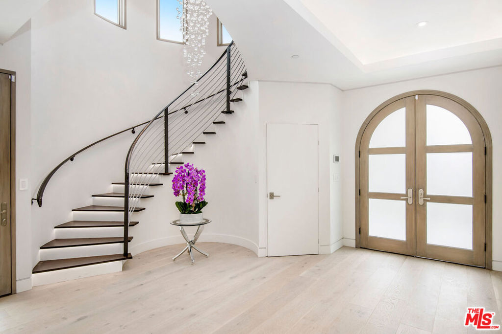 This newly constructed 2021 architectural masterpiece offers 4,000 square feet of luxurious living space with 4 bedrooms and 5 bathrooms, meticulously designed with cutting-edge technology and flawless craftsmanship. Light-filled and expansive, the open-concept floor plan features soaring ceilings and disappearing glass walls that create a seamless indoor-outdoor flow, blending refined interiors with serene resort-style exteriors.Step outside to your private oasis a softly blue-lit infinity pool with tranquil waterfall, fire pit, and lush garden lounge surrounded by blooming flowers and mature fruit trees. Designed for both relaxation and entertaining, this tranquil escape offers the perfect blend of modern luxury and natural beauty.Inside, a dramatic skylit foyer welcomes you with a floating staircase and a stunning 12-foot chandelier. Natural woods and imported stone flow throughout the main level, which includes a stone-clad living room, formal dining room, versatile den, cozy family room, and a gourmet chef's kitchen with custom cabinetry, dual refrigerators and stoves, and three sinks.Upstairs, the elegant primary suite features dual custom walk-in closets and a romantic terrace with views of the lush greenery below. The spa-inspired bathroom includes dual marble vanities, a glass-enclosed shower, and a sculptural soaking tub set in lavish marble.Tucked away on a peaceful, tree-lined street yet just moments from Beverly Hills' top restaurants, markets, shops, Cedars-Sinai, and places of worship, this rare modern retreat offers total privacy in one of the city's most coveted locations.
