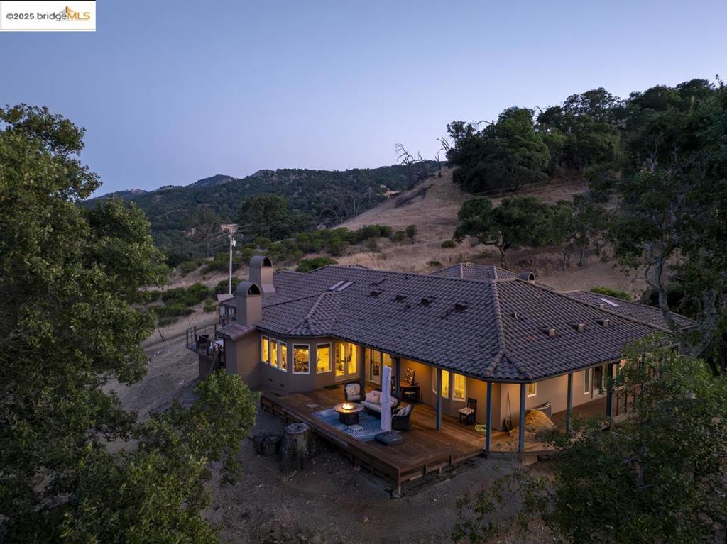 Tucked away on 38+ acres, this extraordinary country hideaway captures the essence of refined rural living, offering panoramic vistas of Mt. Diablo, Mt. Hamilton & surrounding vineyards. The 3,173 sq ft single-level, main residence radiates French country charm with 10-ft ceilings, wraparound verandas, expansive windows. Step into the living room with vaulted wood-beamed ceilings & a fireplace that leads to the chef’s kitchen with an island & wood-burning pizza oven anchoring the adjacent dining room. The layout includes 2 spacious en-suite bedrooms & a bonus room perfect as a third bedroom, office, or studio. The 812 sq ft 2nd home offers 2 beds, 2 baths, living room & laundry—ideal for extended family, guests, or ADU. Outdoors, a 1-acre Cabernet vineyard with over 3,900 vines, temperature-controlled wine cellar, & outdoor kitchen with fireplace are the perfect setting for unforgettable gatherings. Multiple decks & seating areas take full advantage of the tranquil surroundings & striking vistas. Additional amenities include a new, fully paid solar & battery backup system, a 5-car garage, & access to I-80, Lake Berryessa, & major Bay Area airports. A true retreat that seamlessly combines privacy, sophistication, & vineyard lifestyle in one of NorCal’s most picturesque settings.