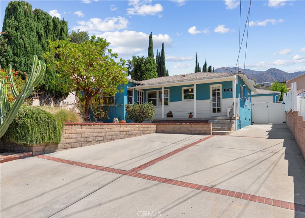Welcome home to comfort and charm on a cul-de-sac—10786 Redmont Ave! Lovingly maintained and thoughtfully updated, this inviting Tujunga retreat offers open living spaces, a spacious lot perfect for expansion, and peaceful outdoor areas designed for relaxation and entertaining—not to mention the mountain views! Venture inside to a bright, open living and dining area with a fireplace—framed by large windows showcasing serene vistas. The fully remodeled contemporary chef's kitchen features stainless steel appliances, quartz counters, soft-close cabinetry, recessed lighting, and under-cabinet lighting—ideal for everyday living and hosting. The remodeled bathroom offers modern fixtures, recessed lighting, and water-saving features. Both bedrooms include double closets and ceiling fans, with expanded hall closets for additional storage. Additional highlights include full copper plumbing, a tankless water heater, newer AC, newer roof and insulation, and original oak hardwood flooring throughout. Outside, enjoy your own private garden sanctuary: three distinct patio areas (including a pergola patio with mountain views), decomposed granite walkways, a two-seater swing, and lush landscaping with jasmine, wisteria, Descanso lilac, lemon tree, rosemary, and native plant xeriscapes. The low-flow automatic irrigation system keeps this hummingbird and butterfly haven flourishing year-round. A two-car garage with plumbing offers potential for an ADU (buyer to verify) or workshop, with compressed air fittings. With its thoughtful updates, spacious lot, and breathtaking views, this turn-key home is the perfect blend of modern comfort, timeless charm, and tranquil outdoor living.